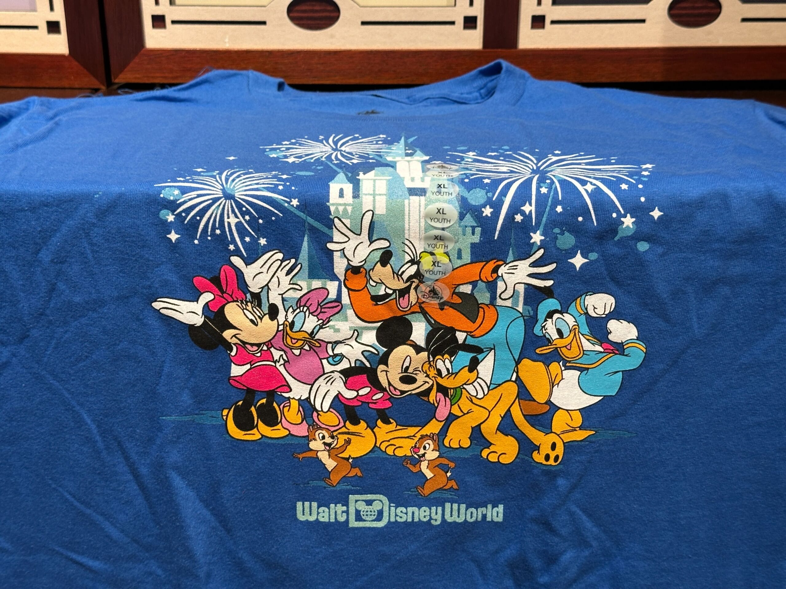 Blue Walt Disney World apparel featuring Mickey, Minnie, Goofy, Donald, Pluto, Chip, Dale, and castle fireworks.