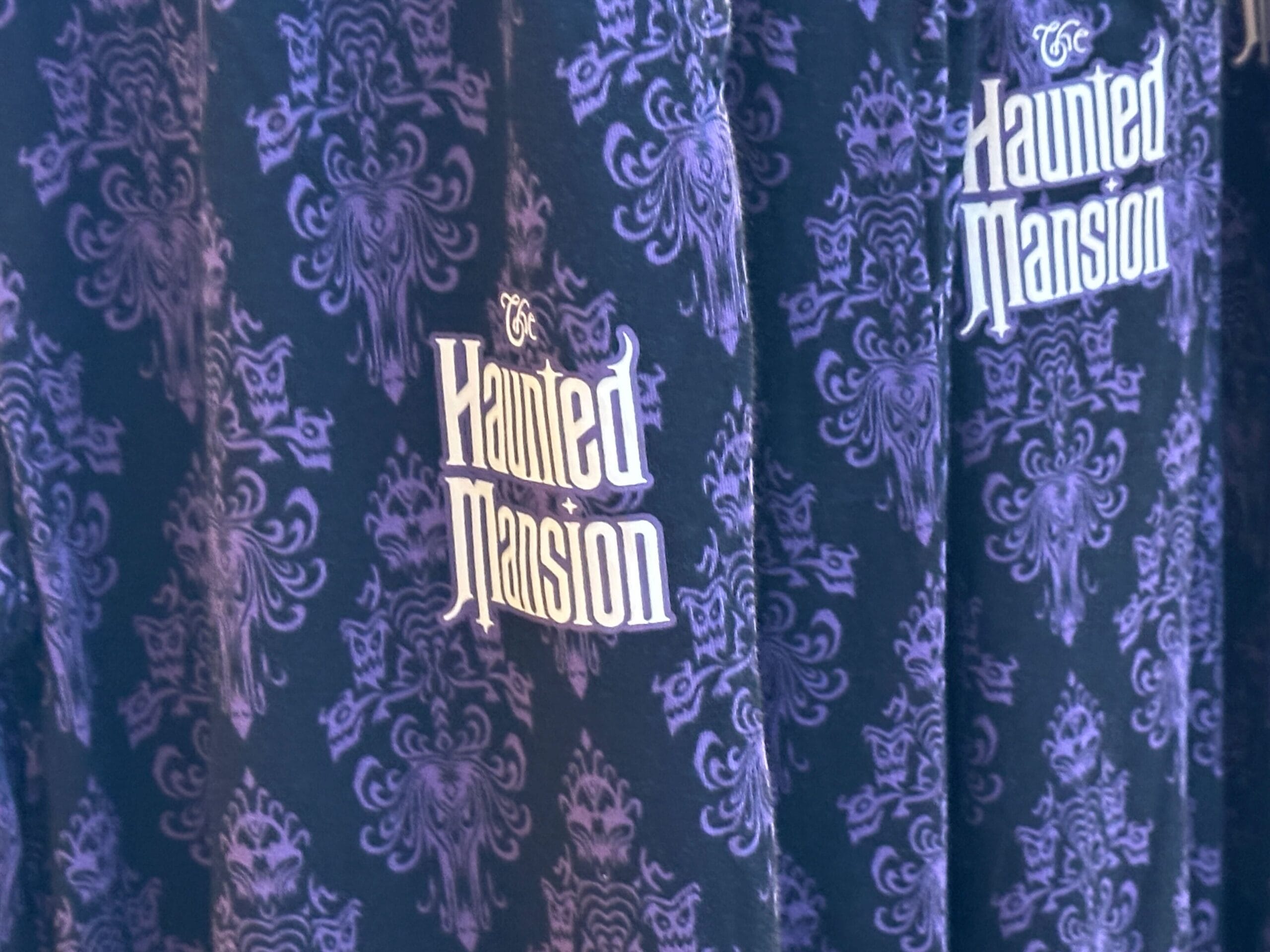 Close-up of new items featuring purple ornate fabric and "Haunted Mansion" wording, inspired by Magic Kingdom.