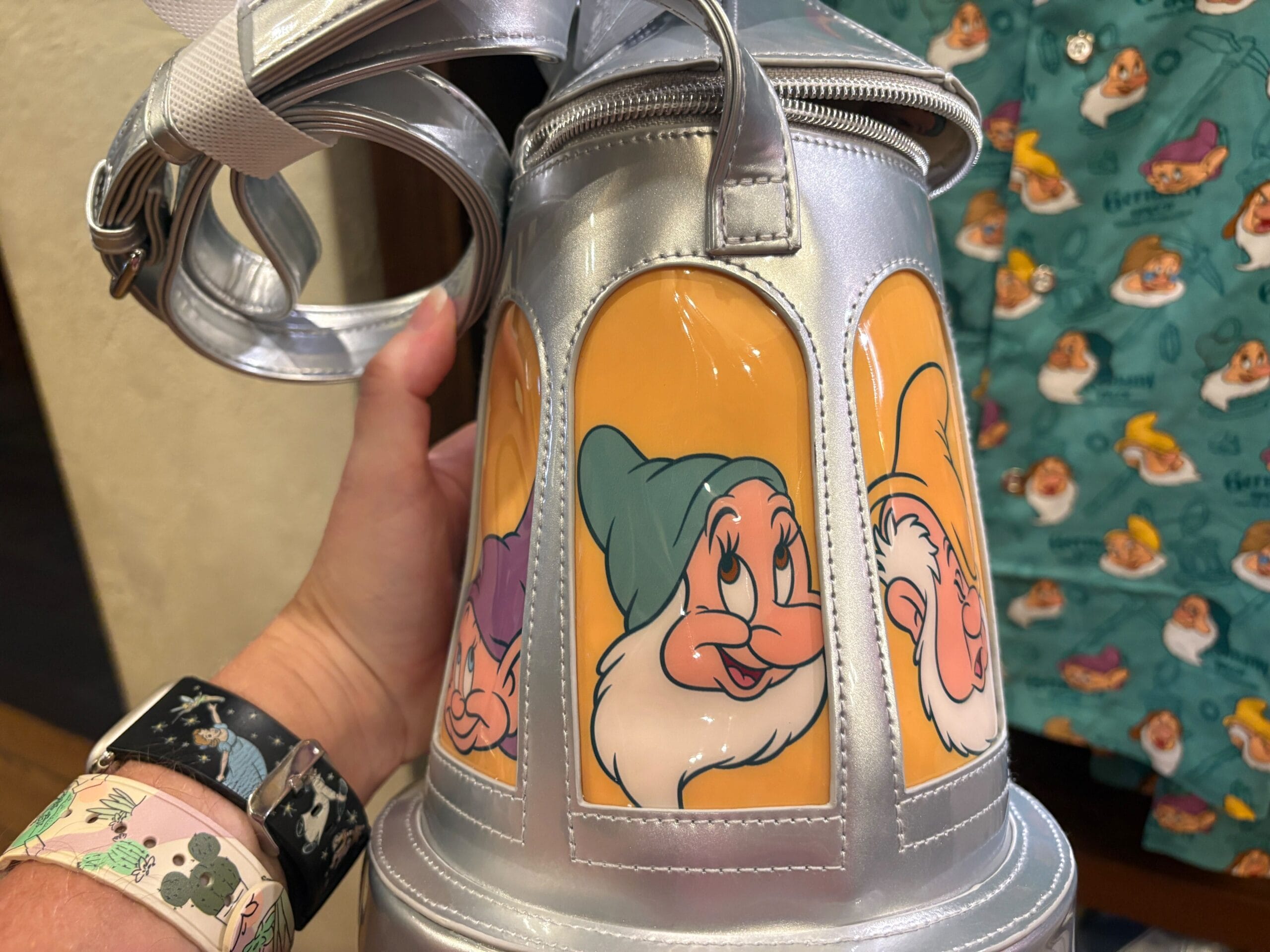 A silver Stein Bag featuring illustrations of Disney’s Seven Dwarfs, including Dopey, Bashful, and Doc, held by a hand.