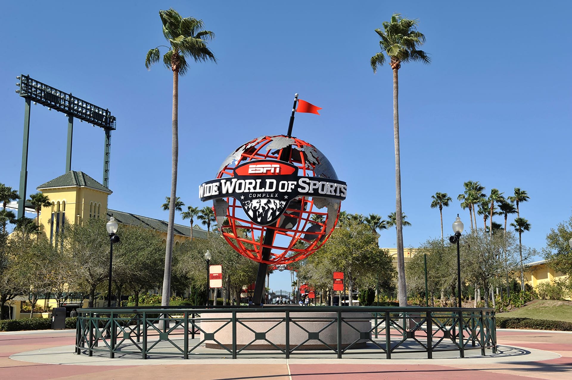 Large ESPN Wide World of Sports globe sculpture surrounded by palm trees under a clear blue sky.