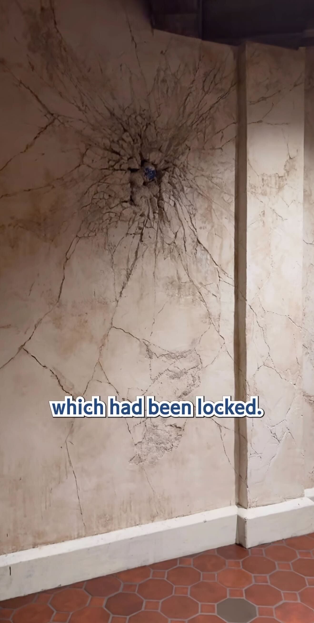 A cracked wall with a large impact mark at the center, like a secret in the pirates tavern; text reads "which had been locked.