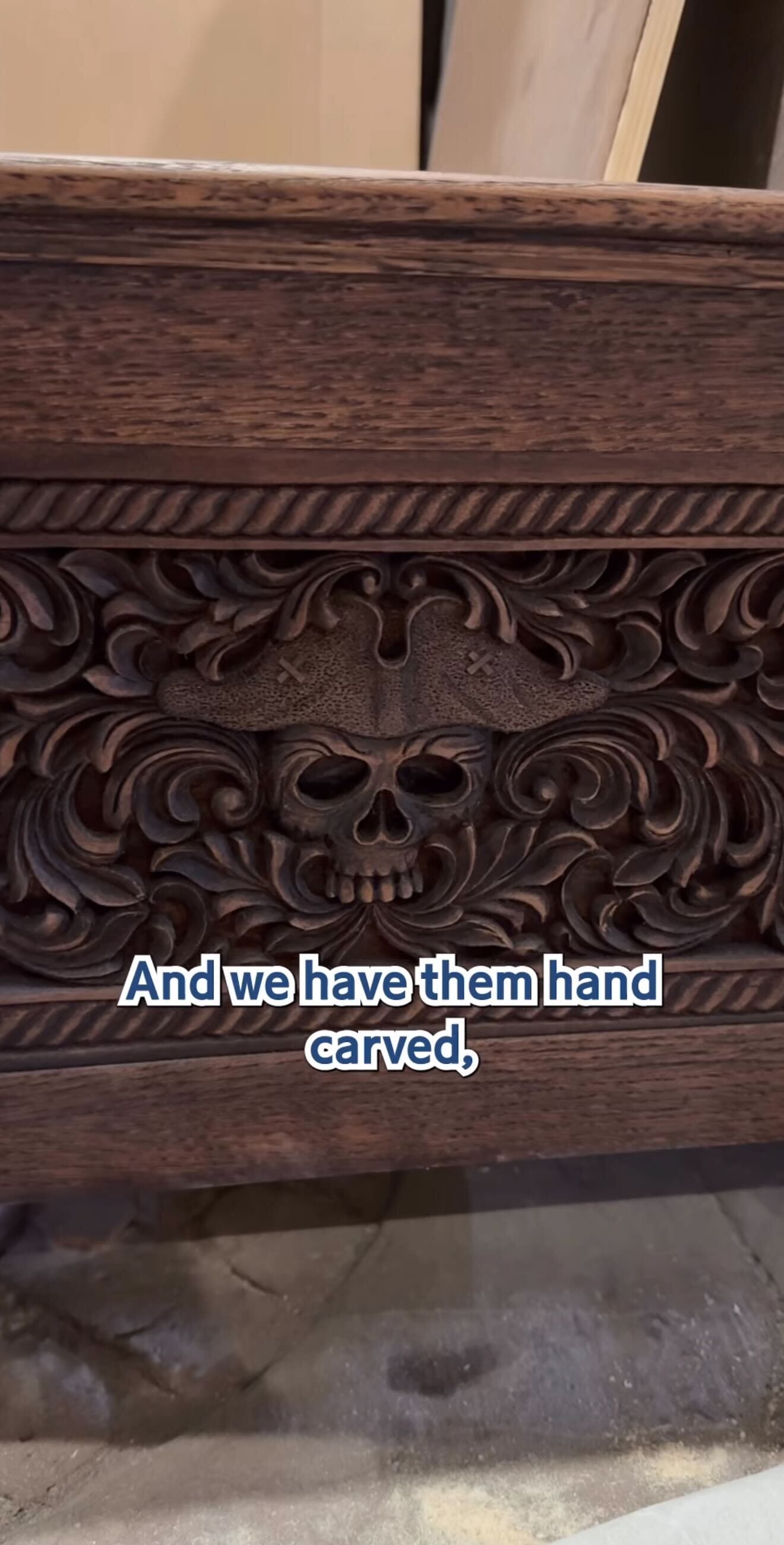 Ornate wood panel with a carved skull, floral designs, and "And we have them hand carved," at Pirates Tavern.