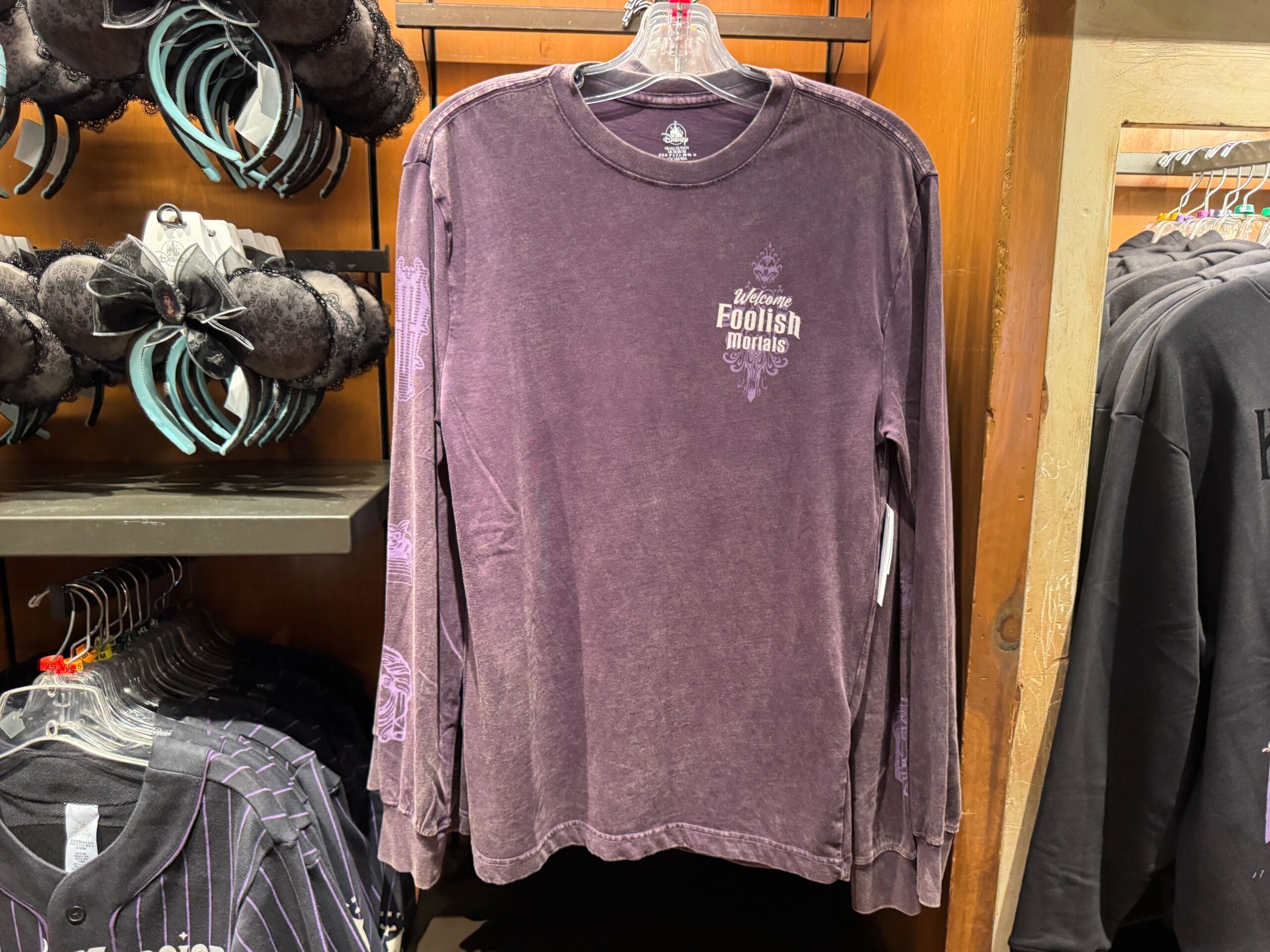 Purple long-sleeve Haunted Mansion merch with "Welcome Foolish Mortals" on the chest, perfect for Magic Kingdom fans.
