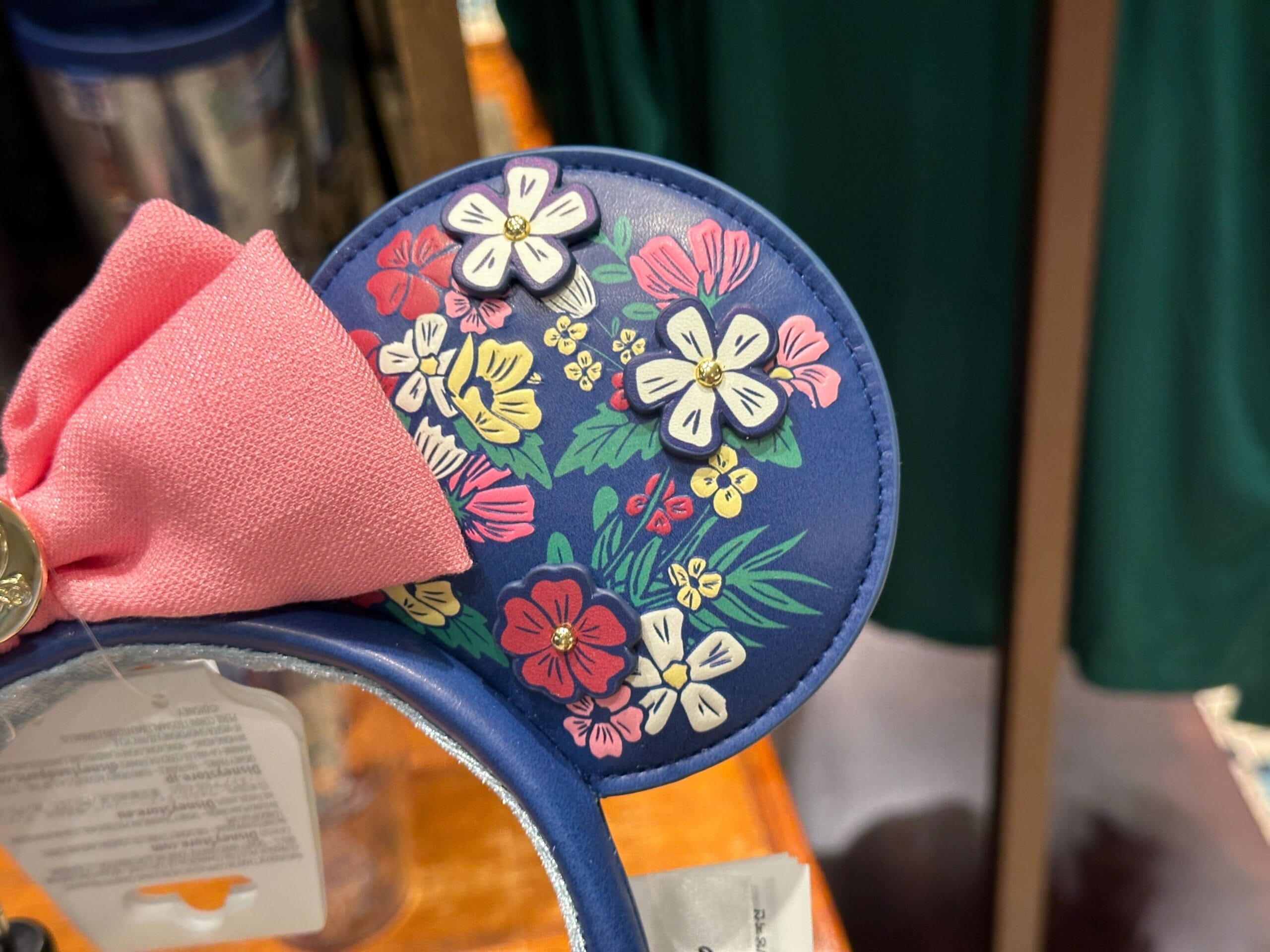 Blue Minnie Mouse ear with a pink bow, decorated with colorful floral patterns and white flowers.