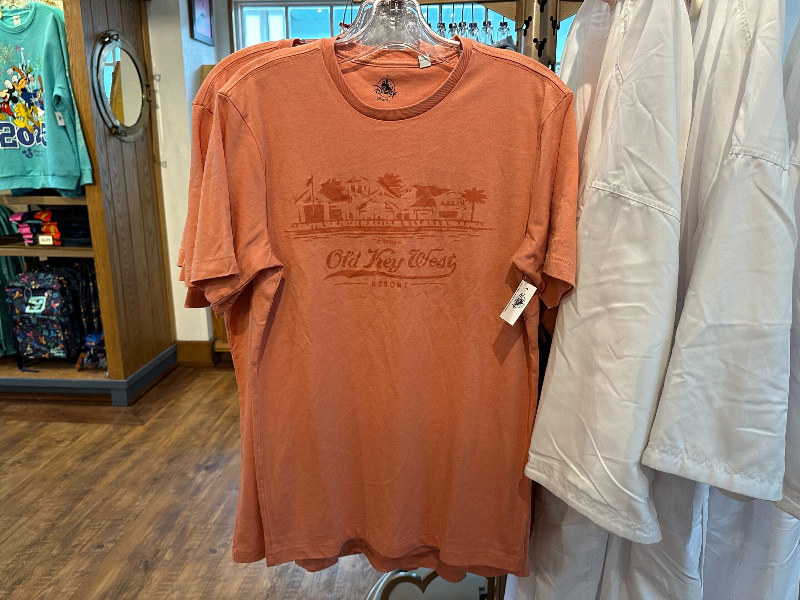 Old key west resort disney apparel Coral Old Key West Resort t-shirt from Disney Vacation Club Apparel, displayed on a rack among other clothing.