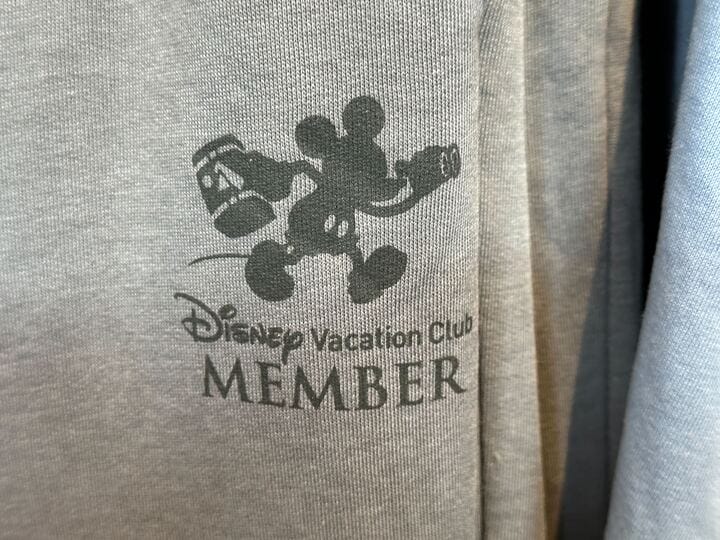 Gray fabric Old Key West T-Shirt featuring Mickey Mouse with luggage and “Disney Vacation Club MEMBER” text printed on it.