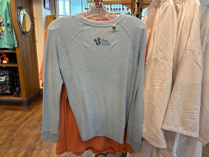 Light blue Old Key West T-Shirt with Disney Vacation Club Member logo on back, hanging on a store rack.