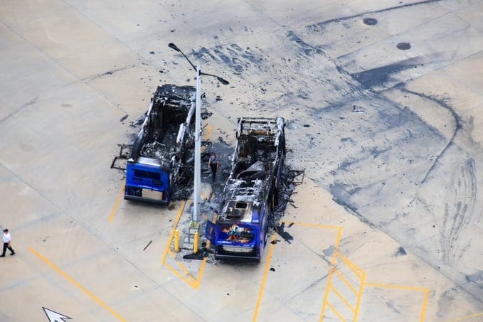 Aerial view of the Universal bus fire in a parking lot, surrounded by black scorch marks on the ground.