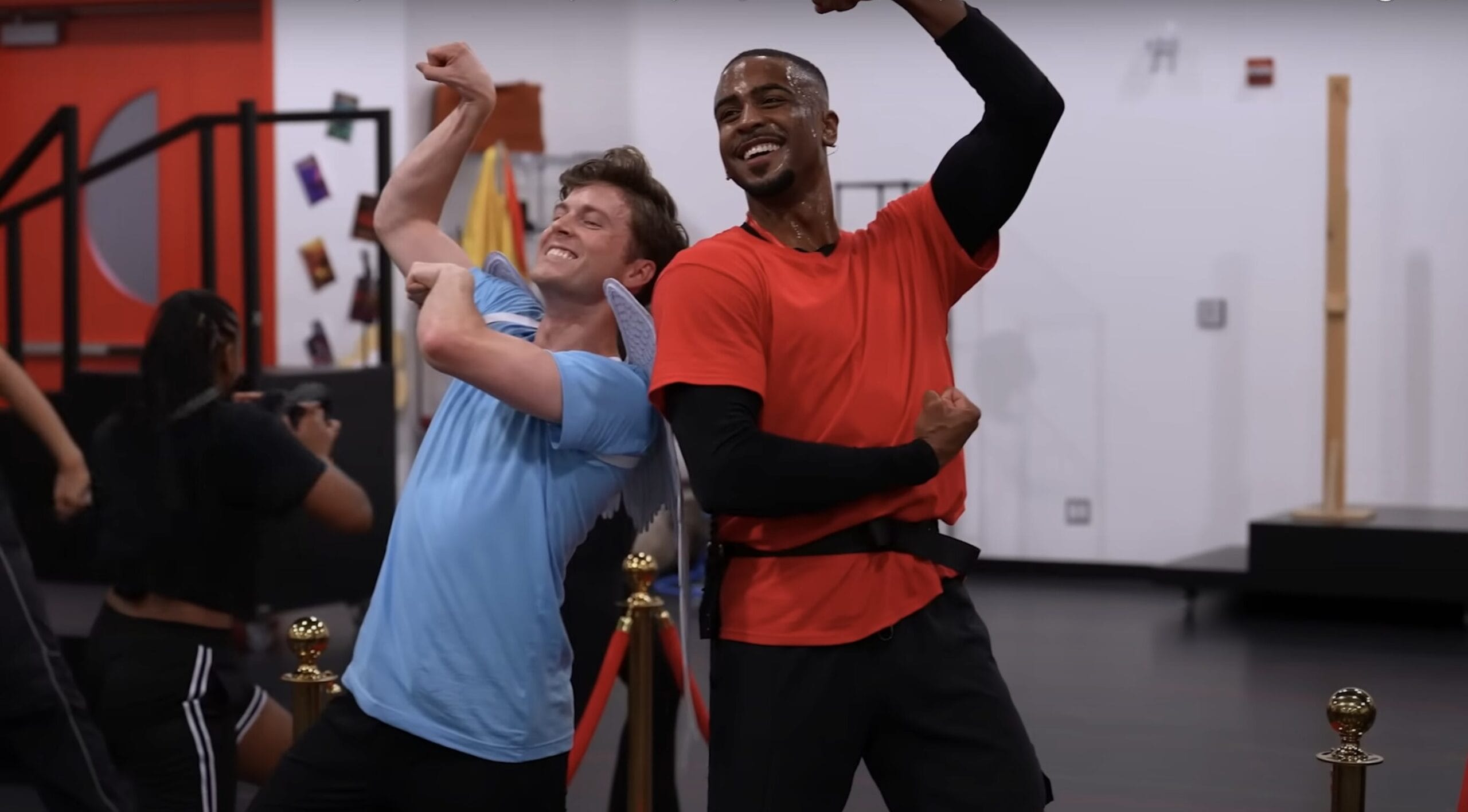Two men smiling and flexing at the gym, channeling Zero to Hero energy from the Hercules Stage Show.