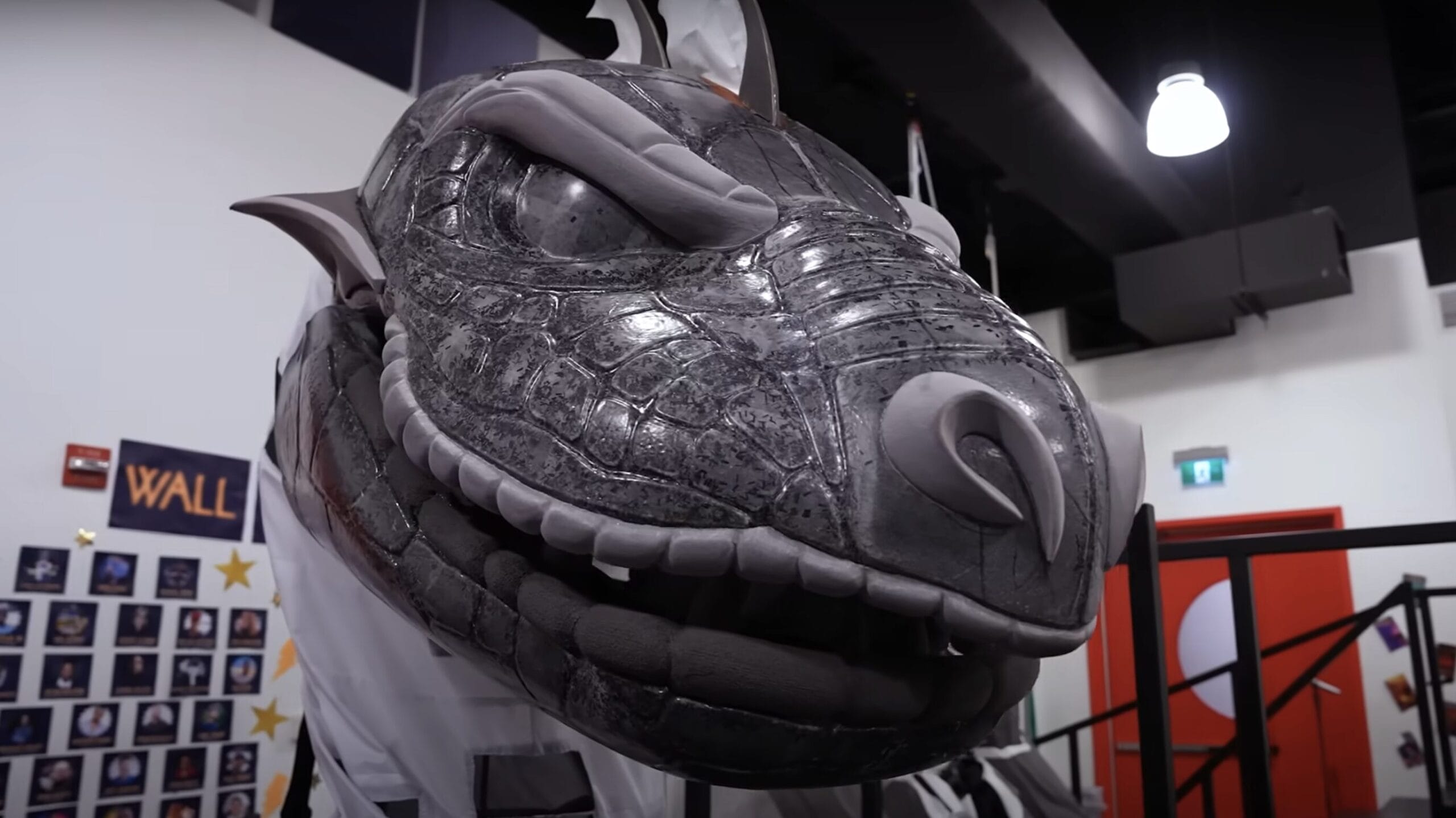 Large gray dragon head prop with sharp teeth, from the Hercules Stage Show on Disney Cruise Line, displayed indoors.