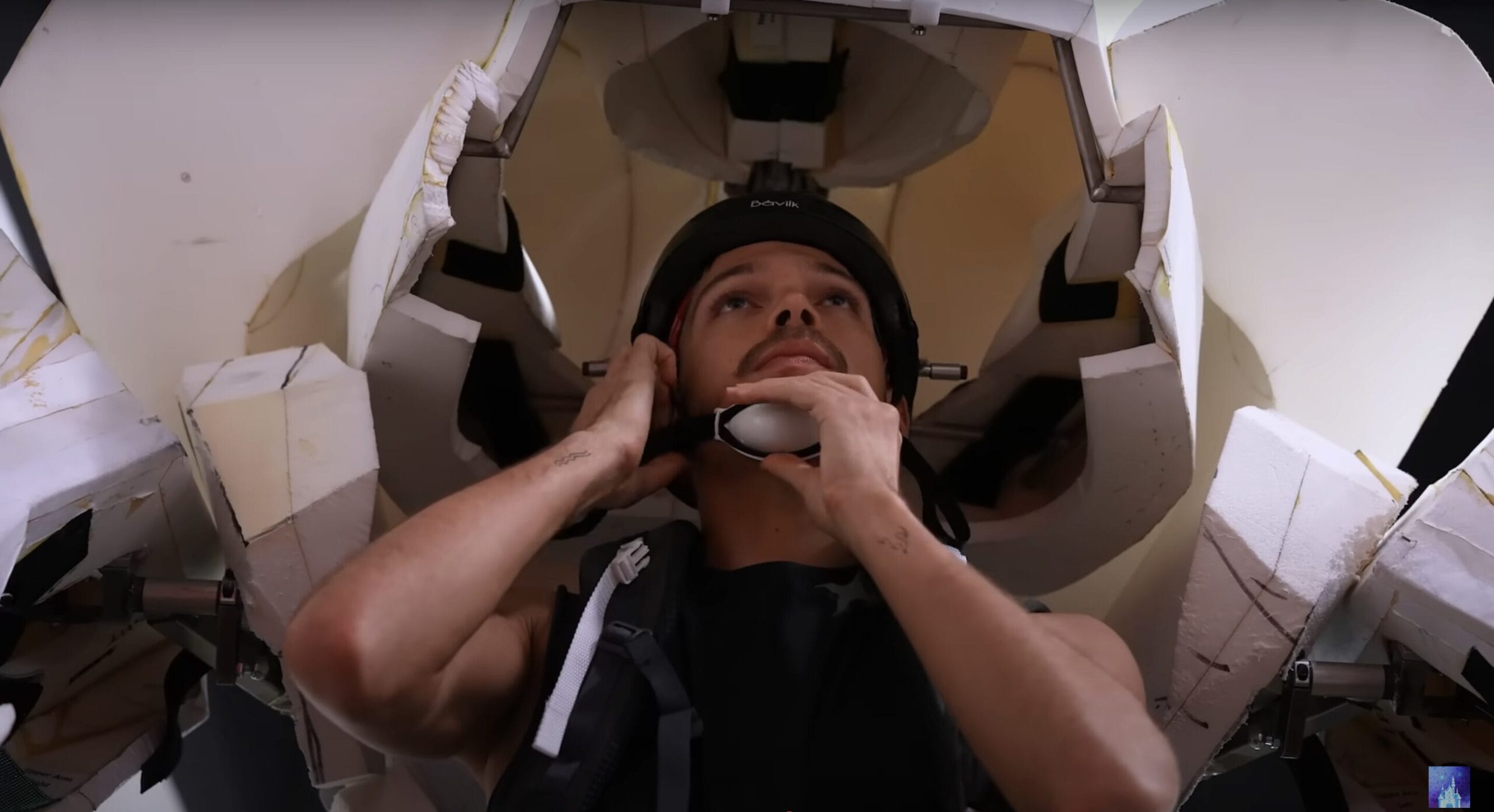 A person puts on a helmet under a large, futuristic structure, ready for the Disney Cruise Line’s Hercules Stage Show.