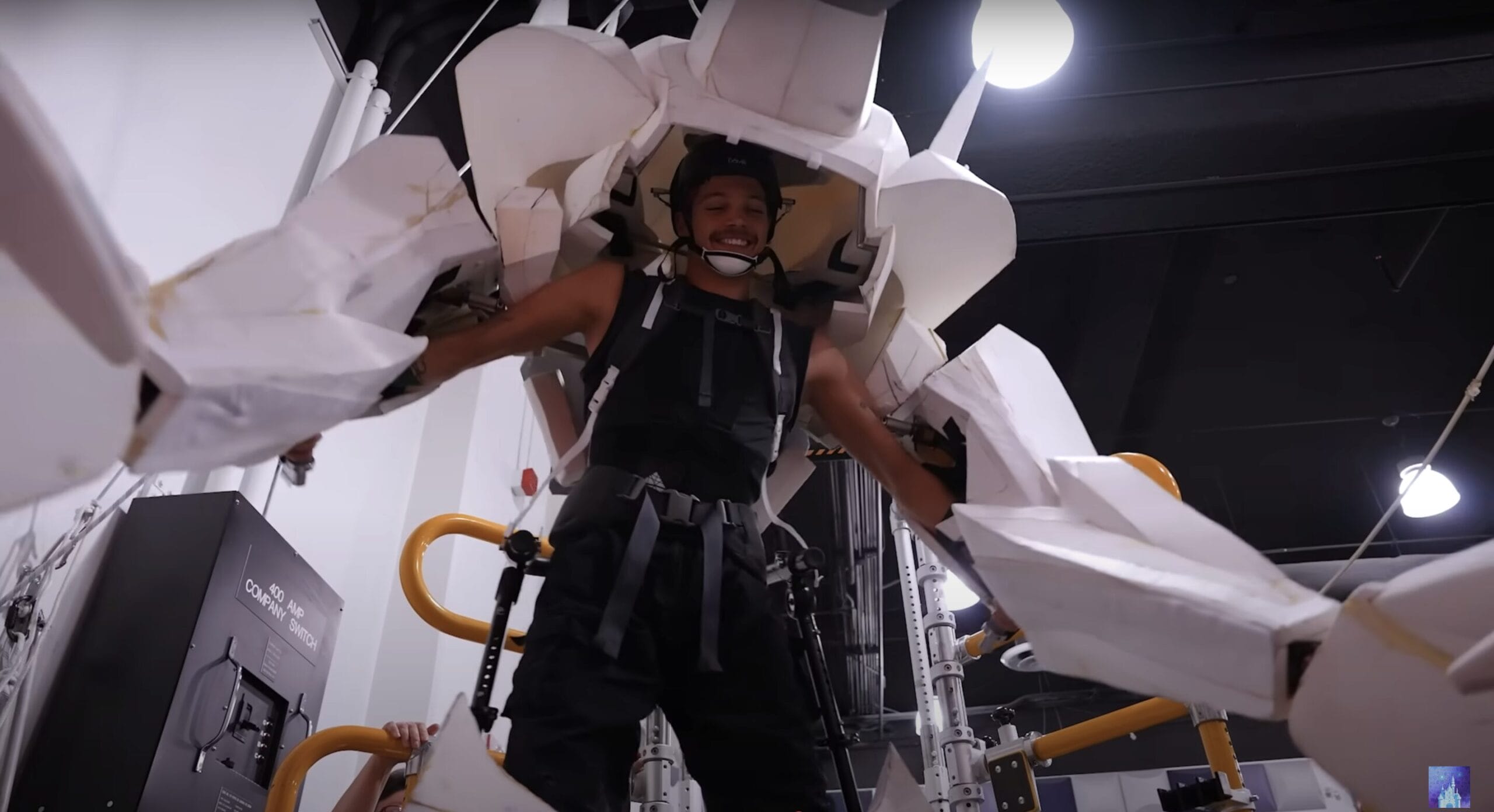 Person smiling indoors in a large, white exoskeleton suit—like a Disney Cruise Line Hercules Stage Show "Zero to Hero" moment.