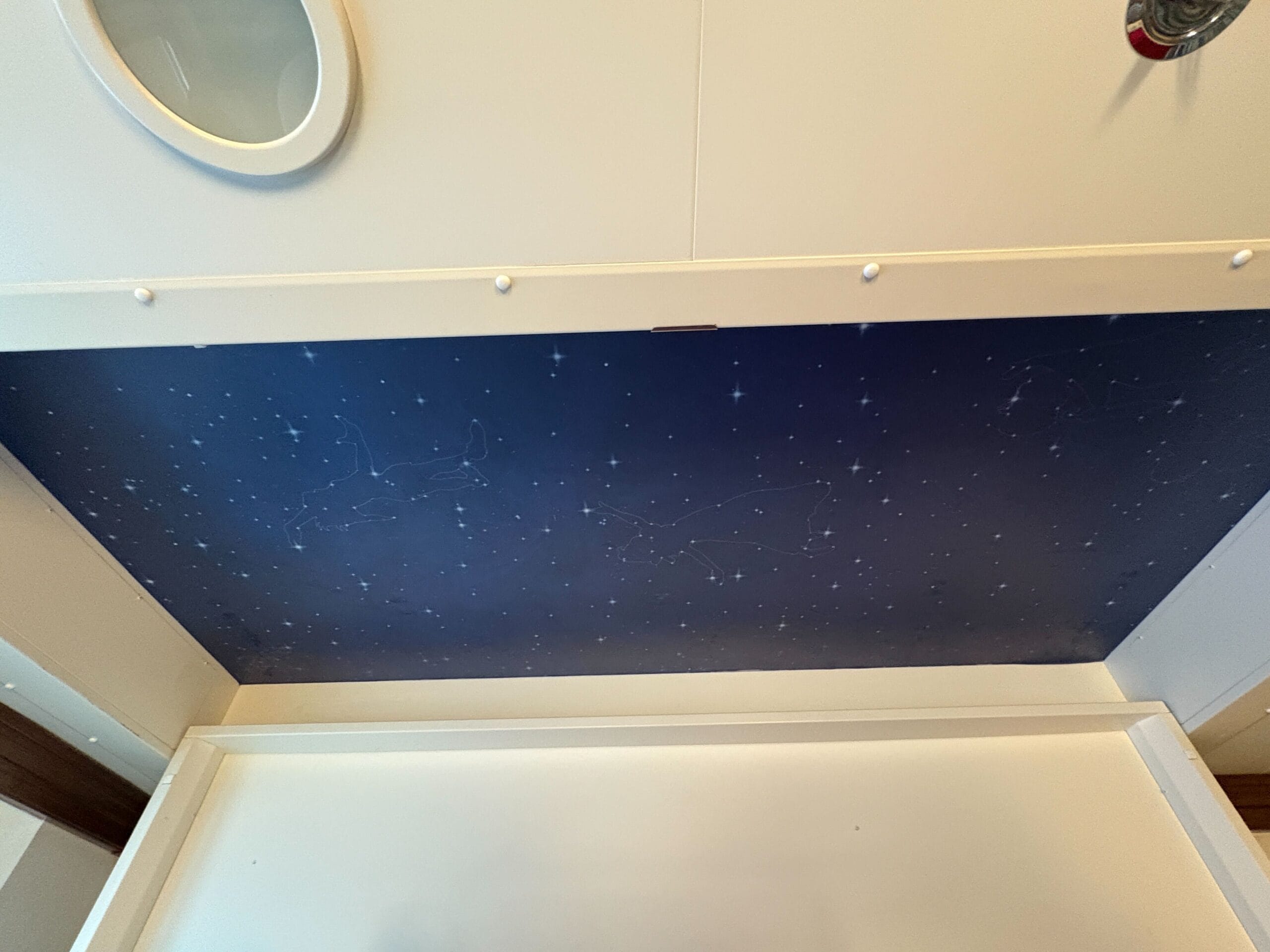 A dark blue ceiling panel painted with stars and constellations, evoking a Disney Dream concierge atmosphere from below.