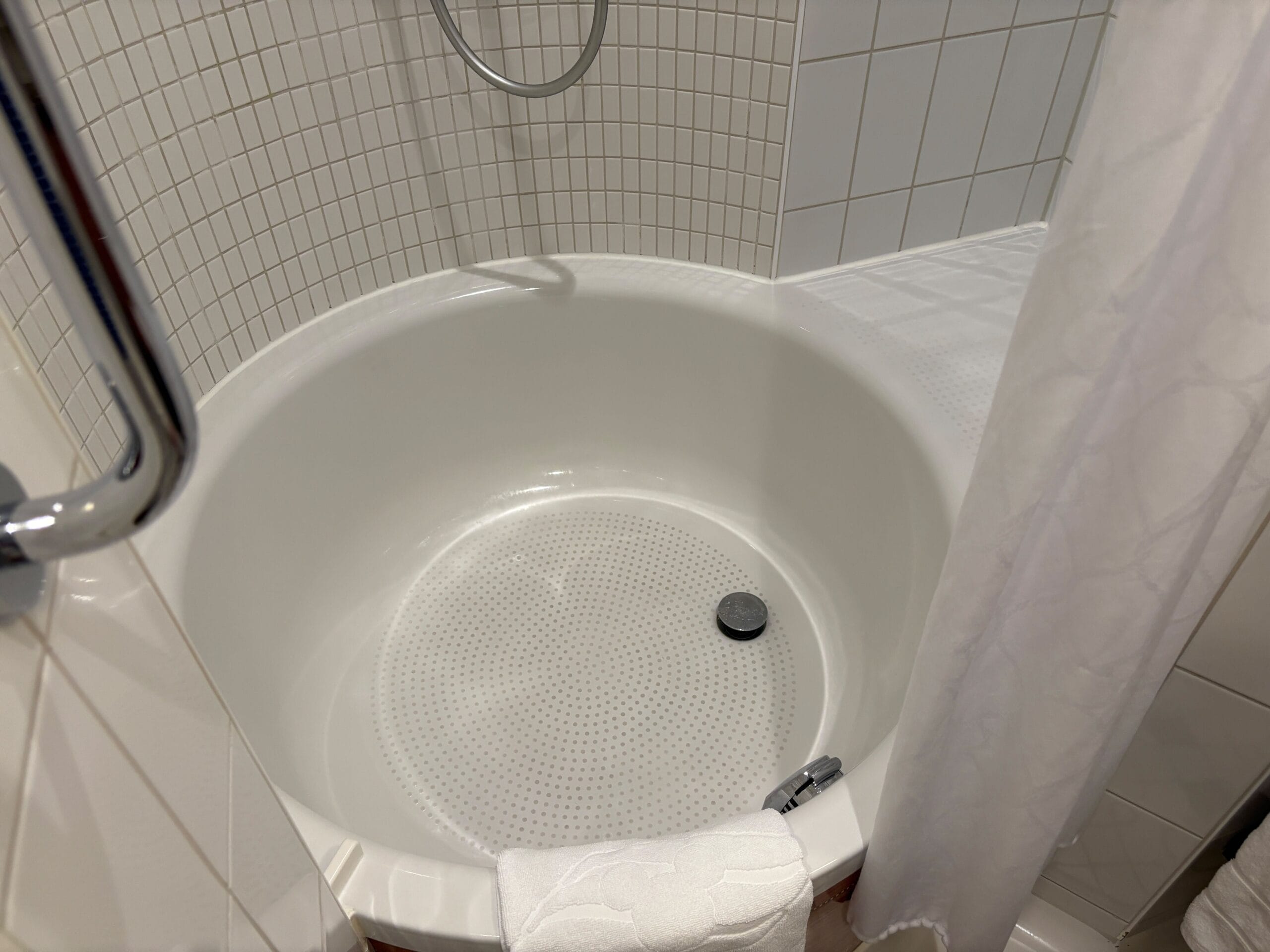 Round white bathtub with a silver drain in the Concierge Family Oceanview Stateroom on Disney Dream Cruise.