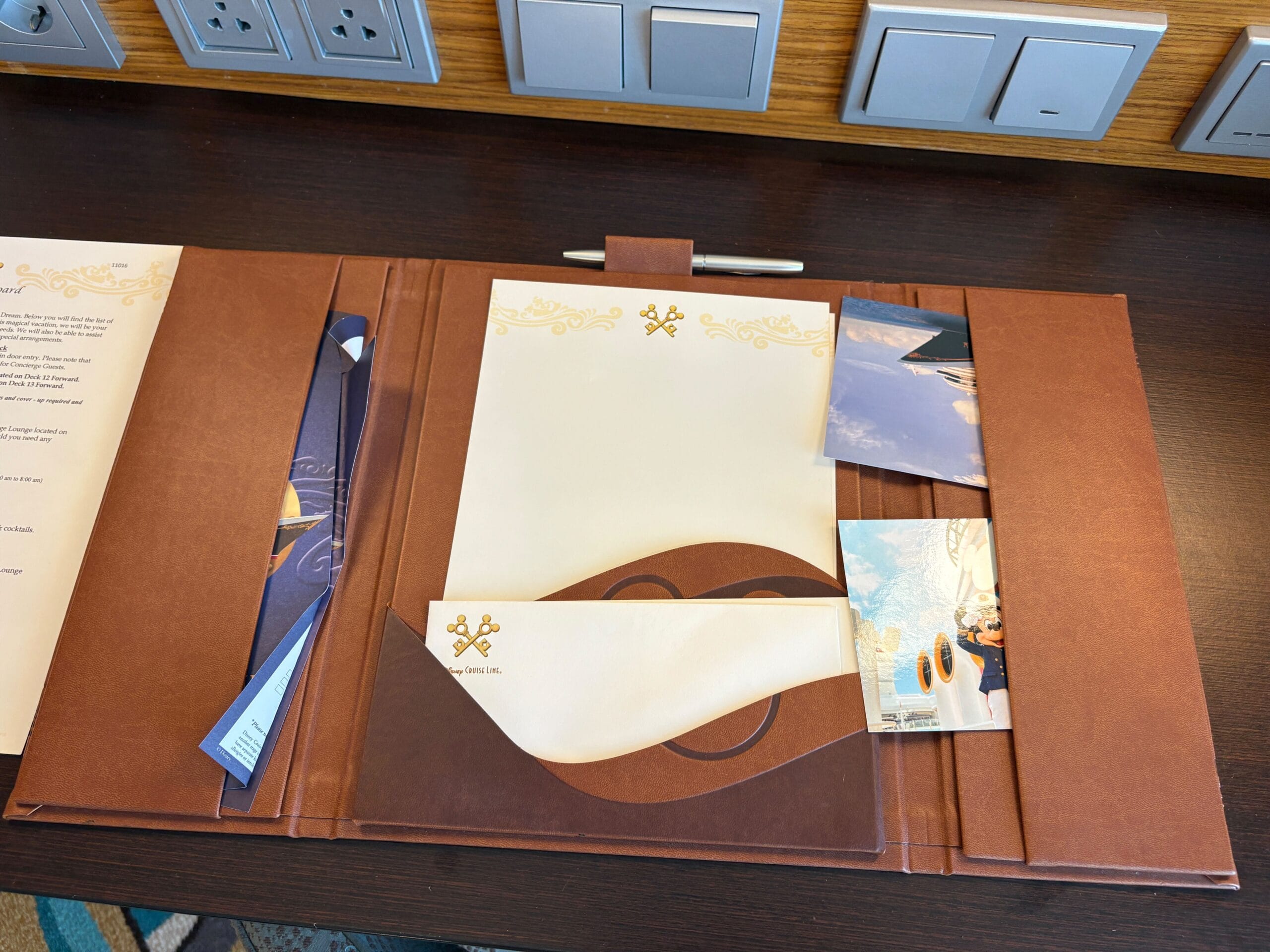 Brown leather folder with stationery and pen in a Disney Dream Cruise Ship Concierge Family Oceanview Stateroom.