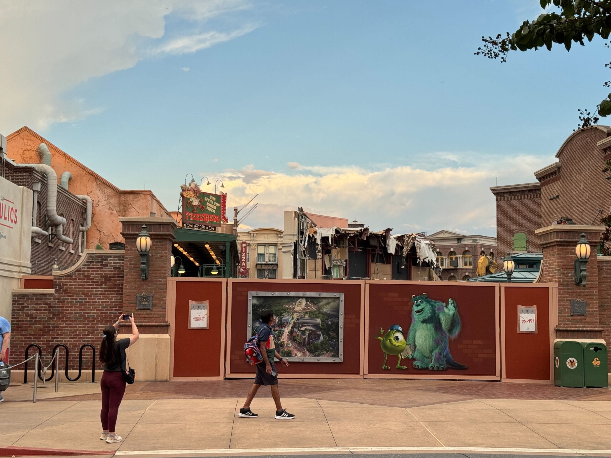 People walk past a demolished wall with Monsters, Inc. art near Disney's Hollywood Studios' Muppets Store.