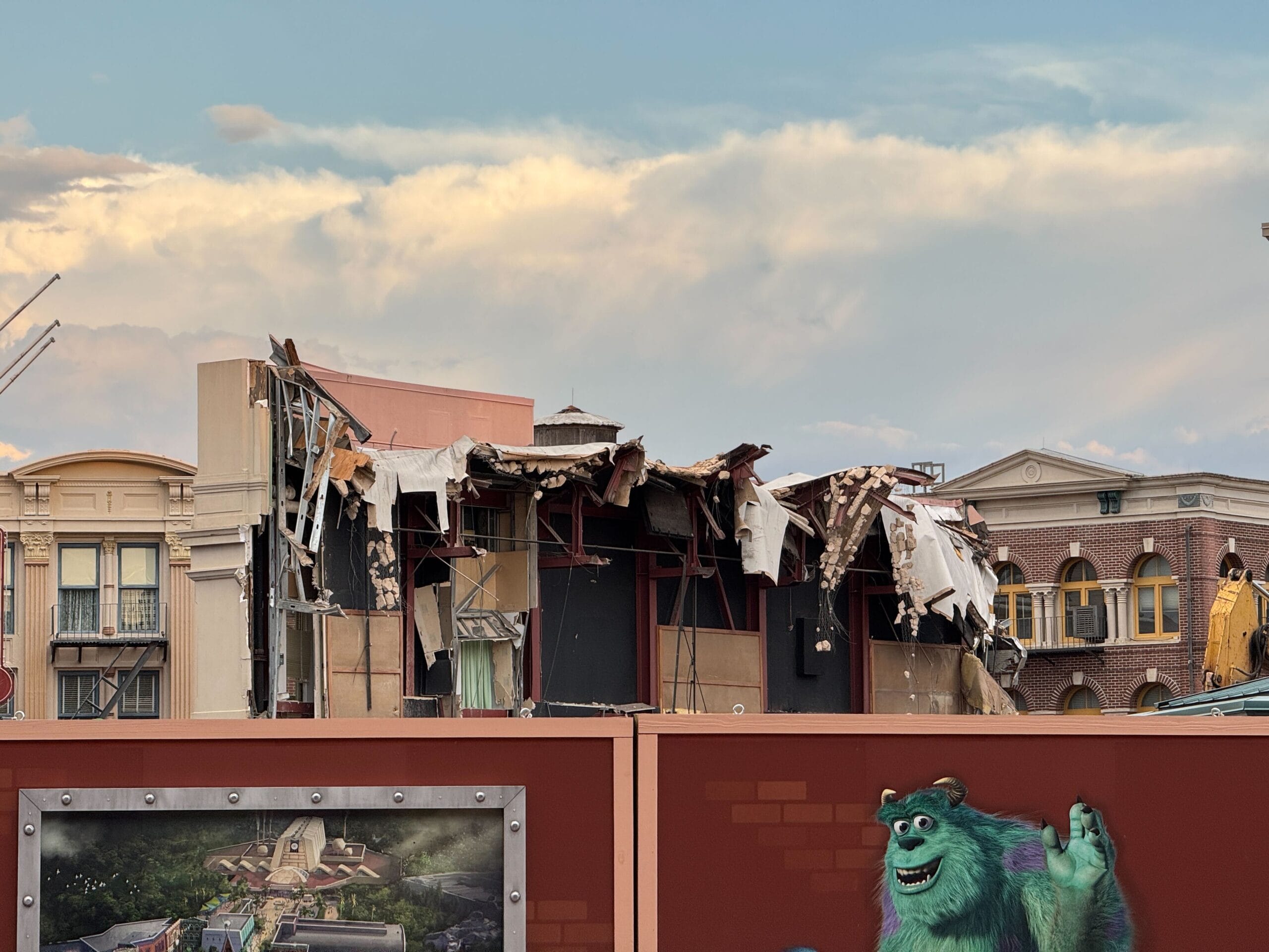 A partially demolished building behind a fence at Disney's Hollywood Studios features a Sulley mural.