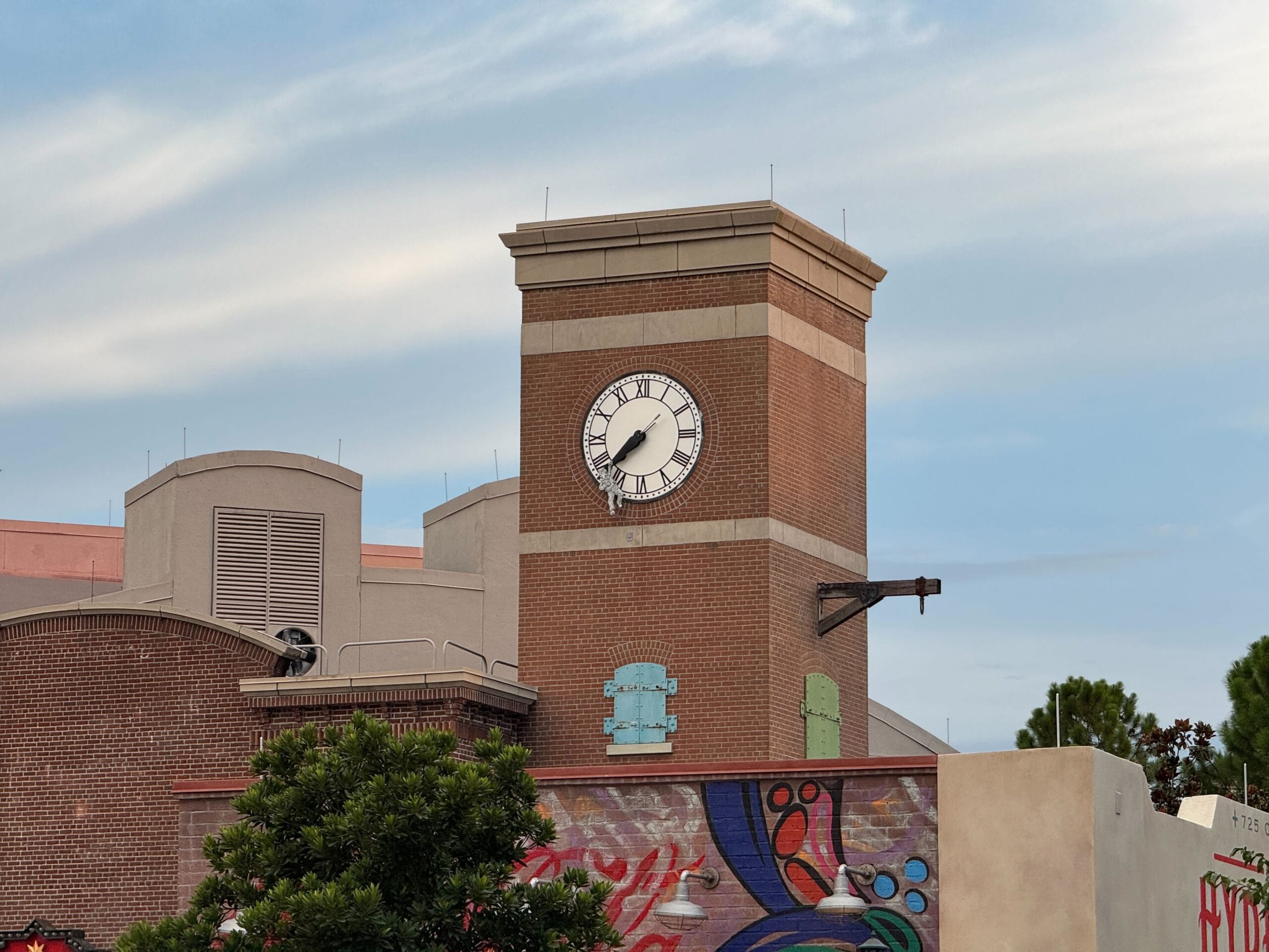 A brick clock tower above the Muppets Store, showing 8:06, stands out against a mural in Disney's Hollywood Studios.