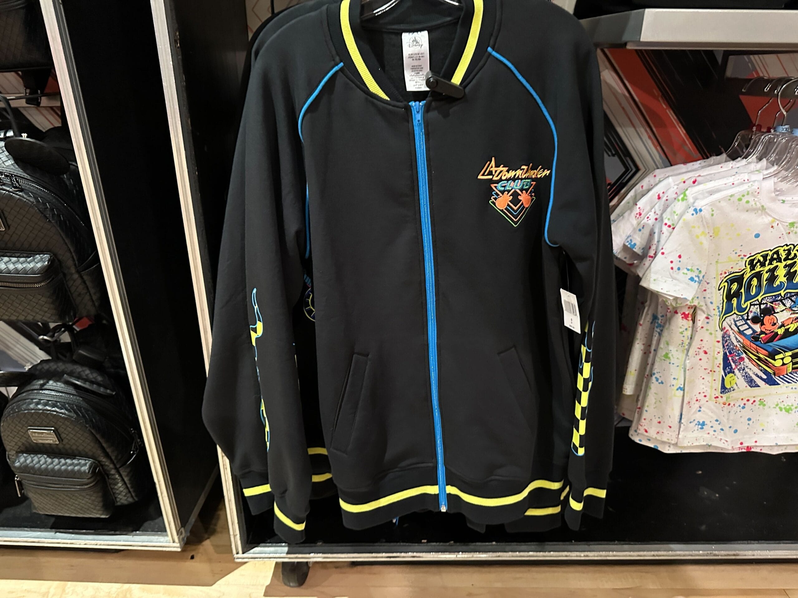 Black “Cosmic Rewind” jacket with yellow trim joins apparel inspired by Rock 'n' Roller Coaster in the store display.