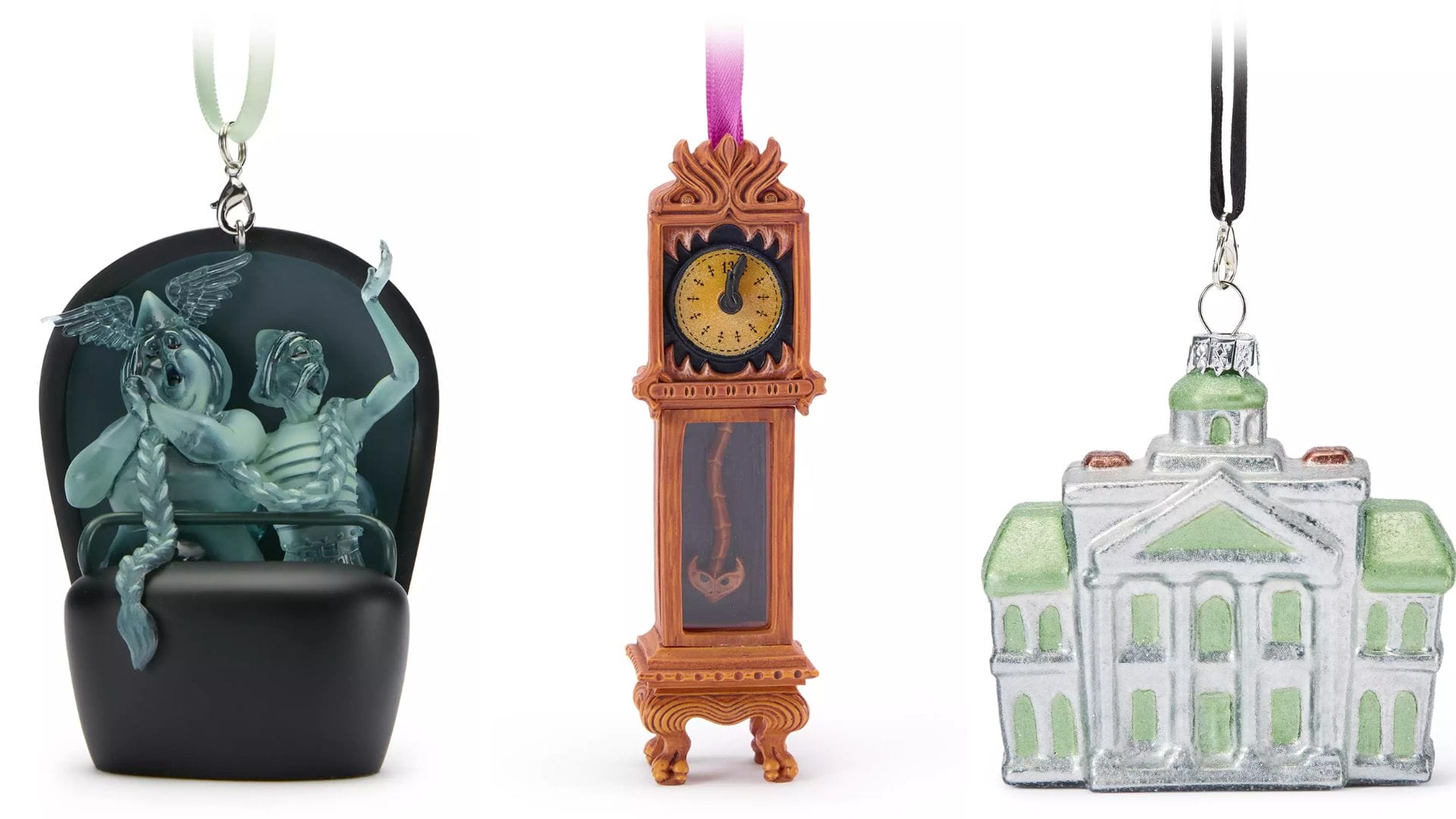 Three Haunted Mansion ornaments: two skeletons in a car, a tall clock, and a green-domed building.