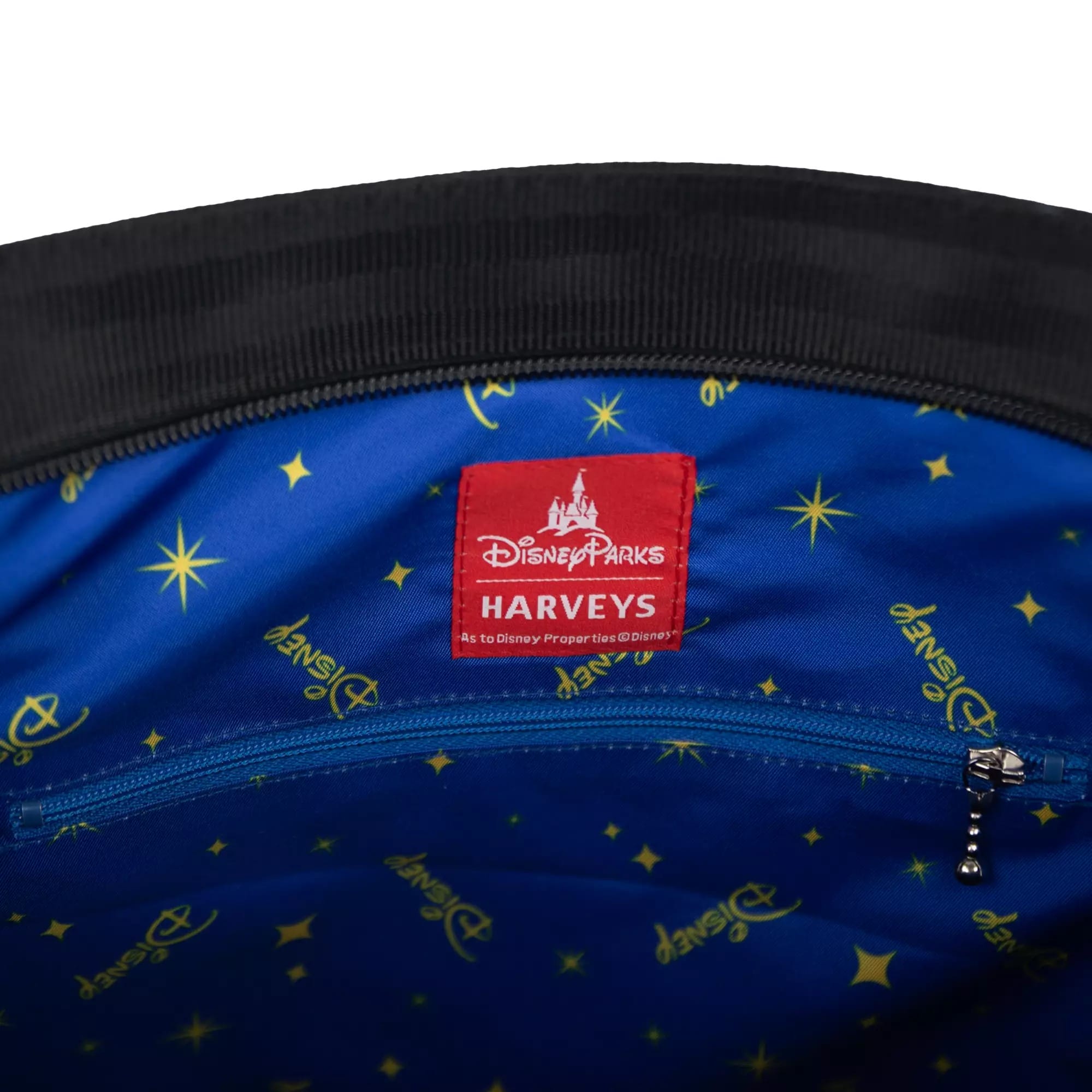Close-up of a blue Disney-themed fabric lining inside a bag, with a red Disney Parks x Harveys label and a zipper.
