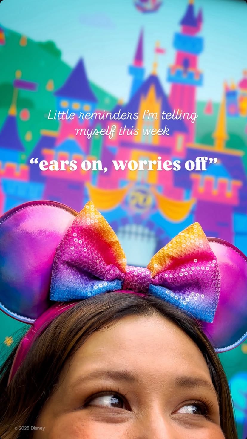 A person wears Disneyland merchandise rainbow Minnie Mouse ears with a colorful castle and "ears on, worries off" text.