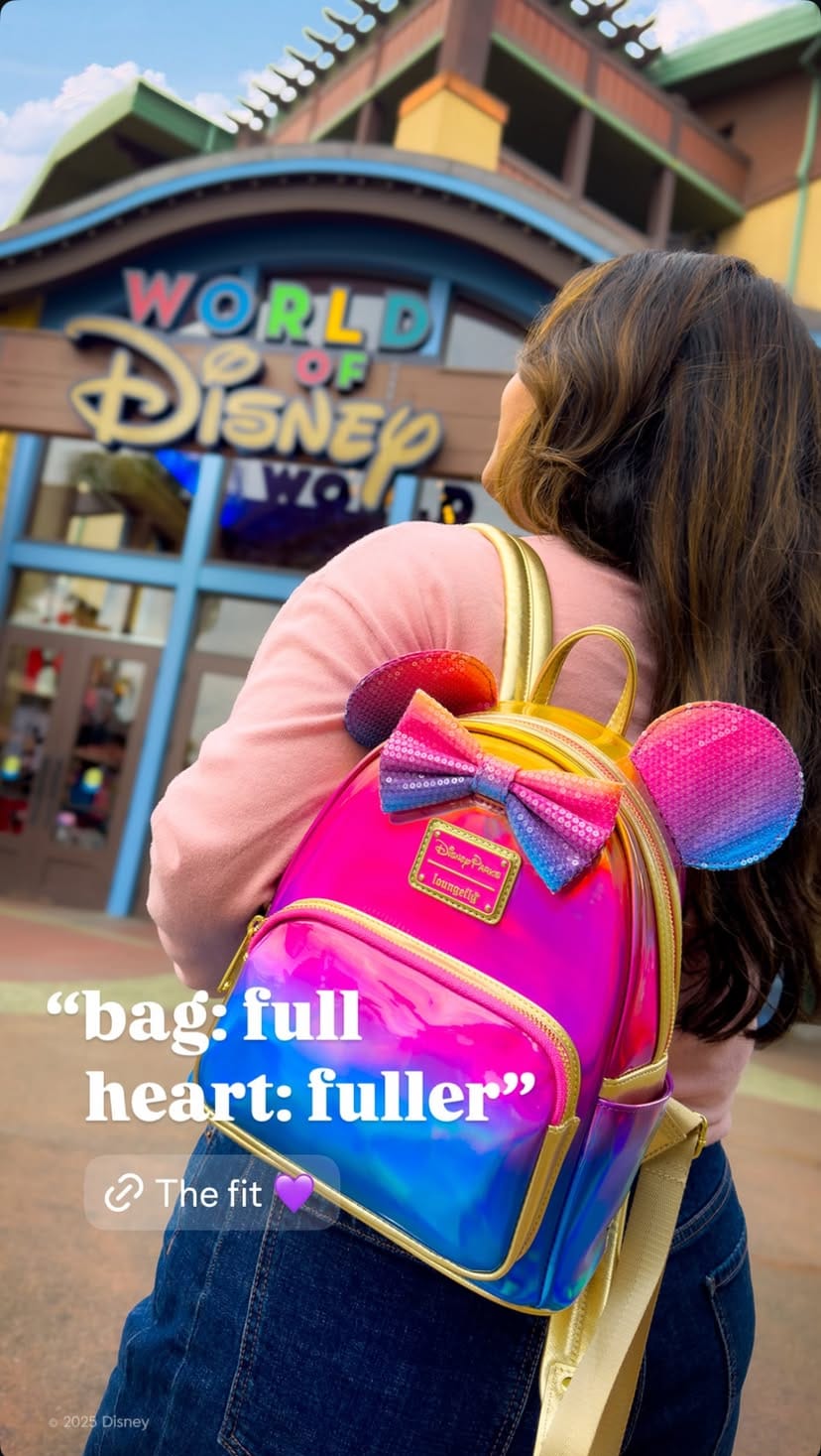 Woman with a Celebrate Happy Merchandise backpack stands in front of the World of Disney store at Disney World.