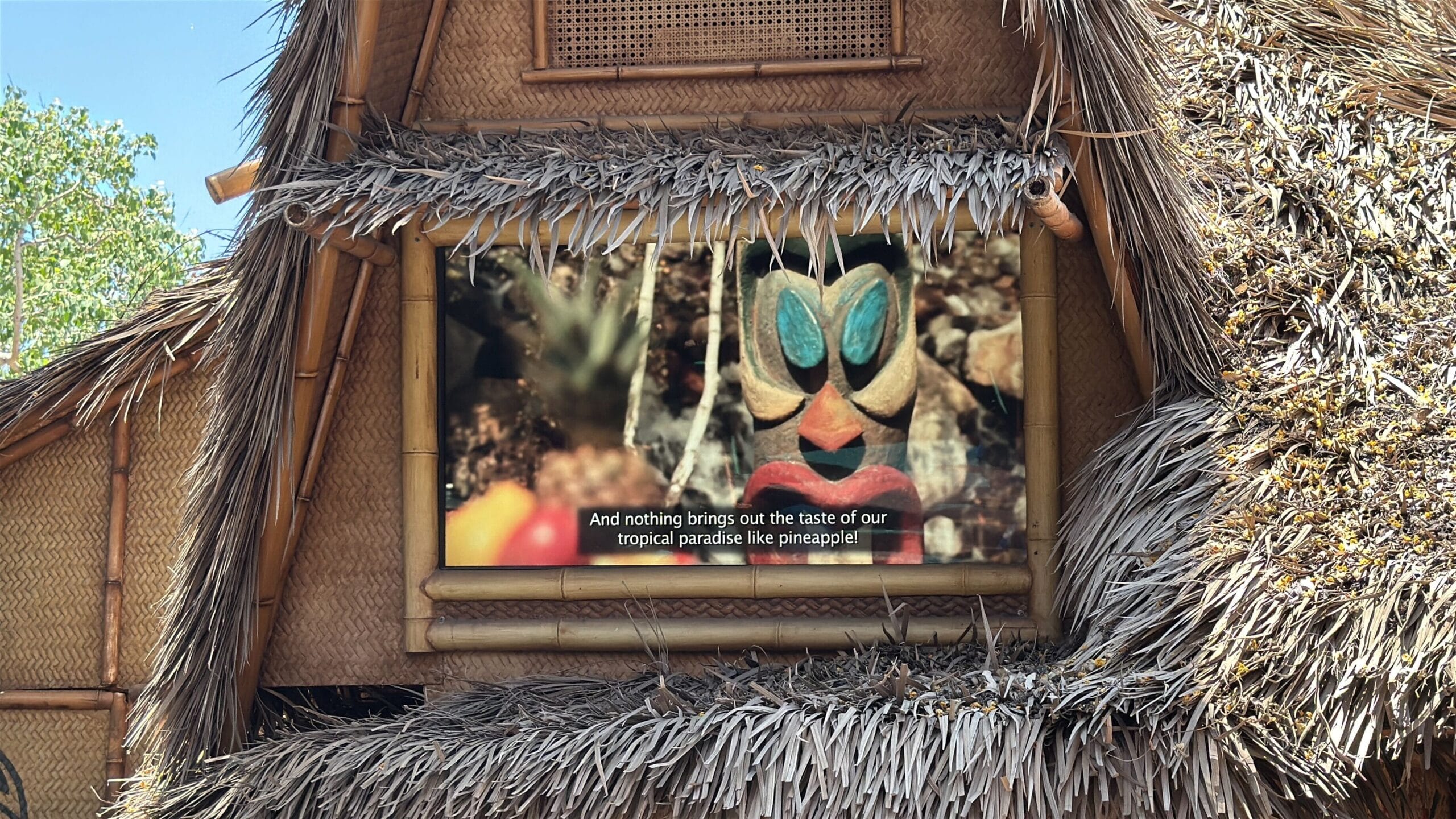 A tiki mask is displayed on a screen at Disneyland's Enchanted Tiki Room, celebrating the reopening with pineapple delights!