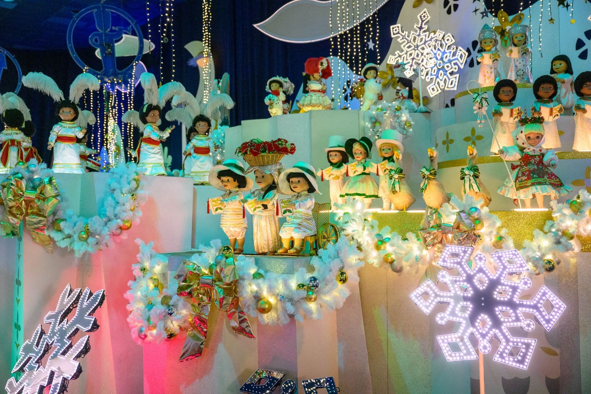 Colorful holiday display of dolls in festive outfits at Disneyland Resort, glowing with 2025 Holidays magic.