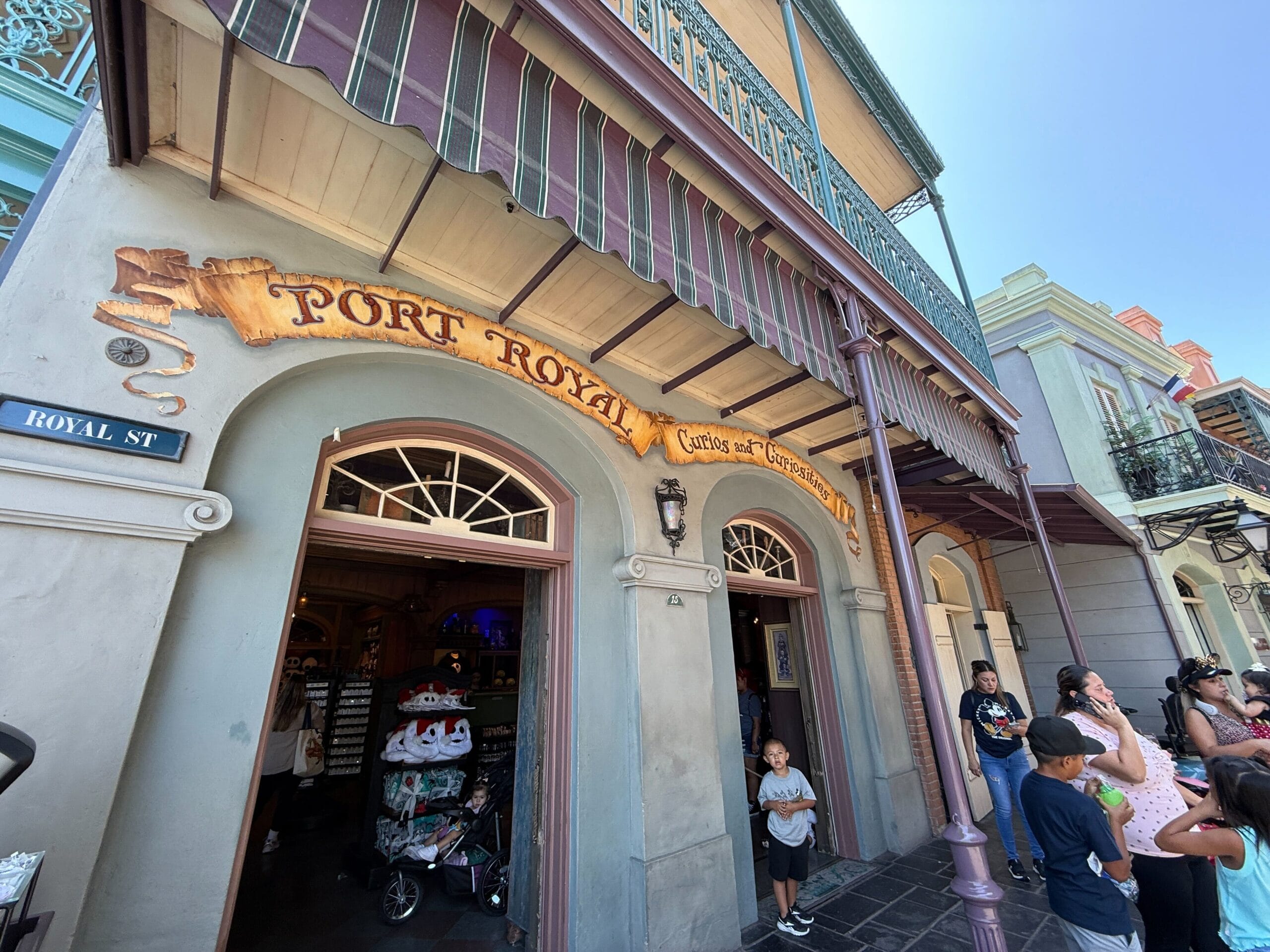 People stand outside the Port Royal Curios and Curiosities shop, browsing Haunted Mansion merchandise on Royal Street.