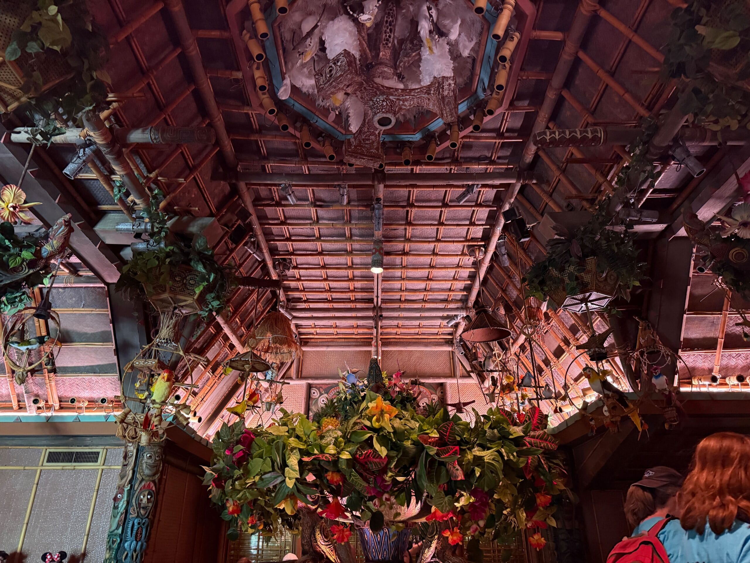 Decorative ceiling with bamboo, plants, and flowers inside Disneyland’s Enchanted Tiki Room during reopening.