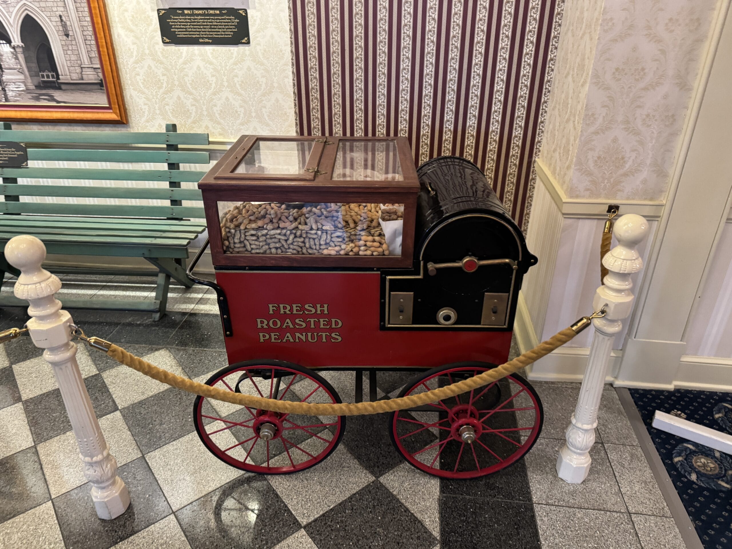 A vintage red cart with "Fresh Roasted Peanuts" is roped off indoors near the Main Street Opera House.