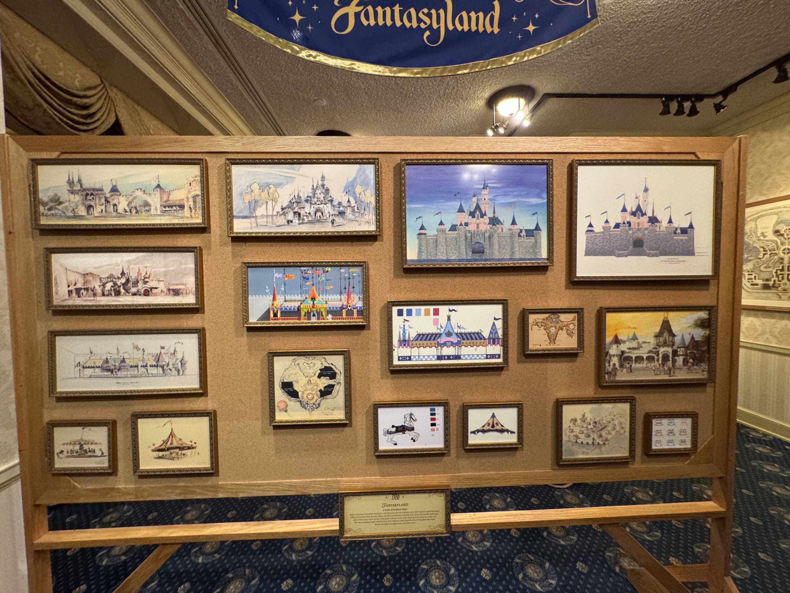 A display board at the Main Street Opera House features new exhibits of Fantasyland photos and concept art in ornate wooden frames.