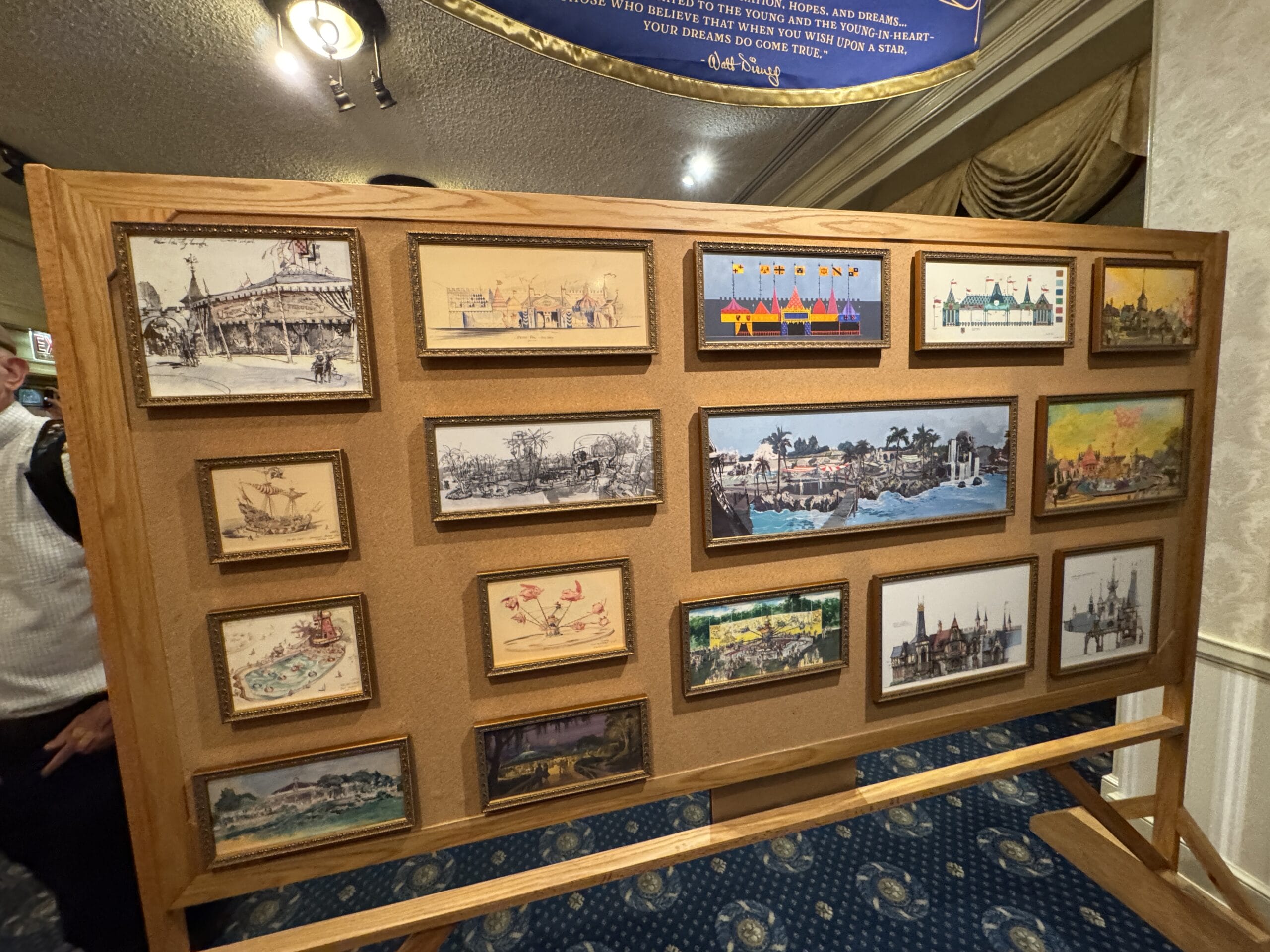 A display board with framed concept art and photos of new exhibits at the Main Street Opera House.