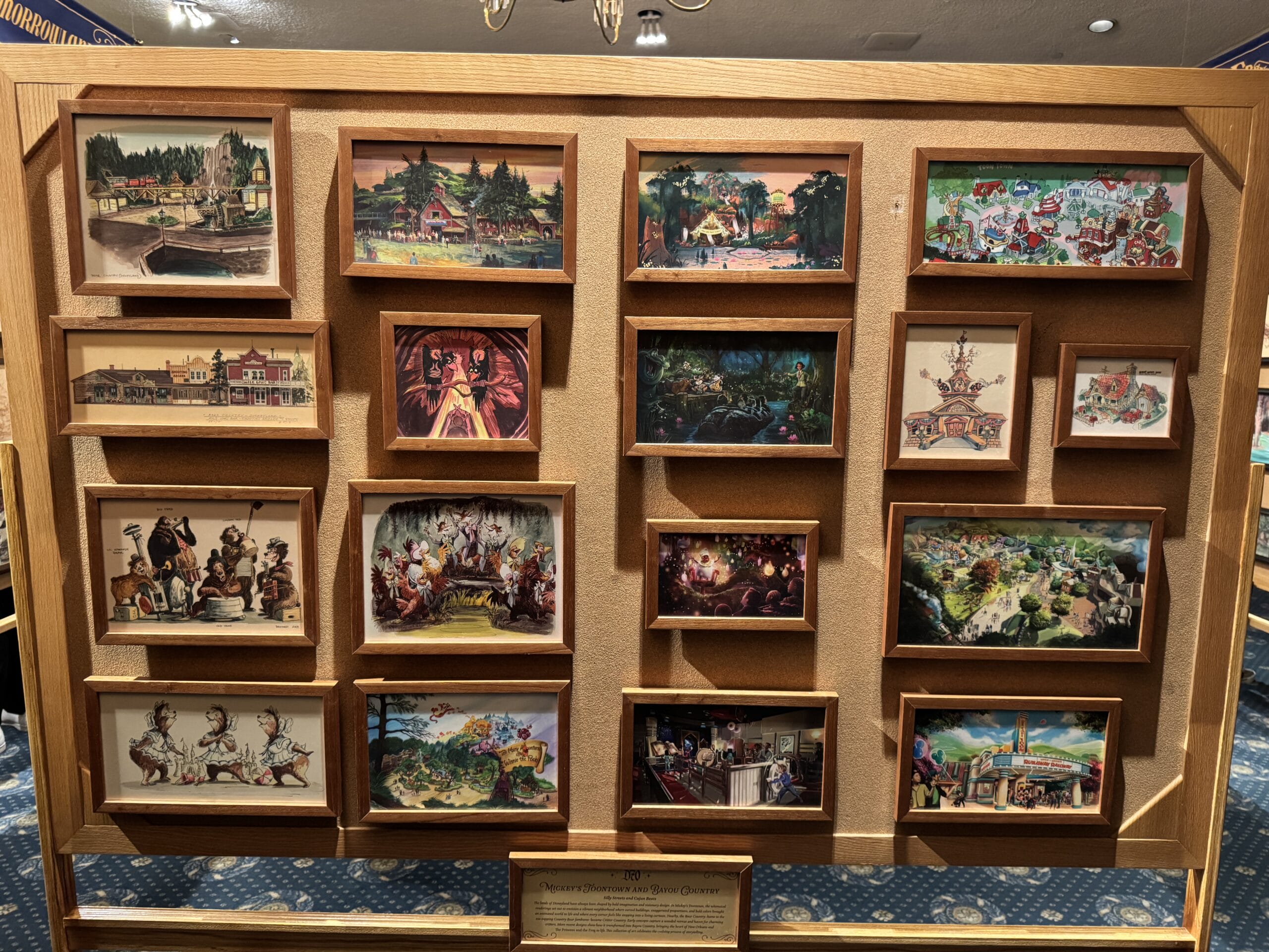 A wooden display case with framed vintage Disneyland postcards, each row capturing colorful scenes from Disneyland history.