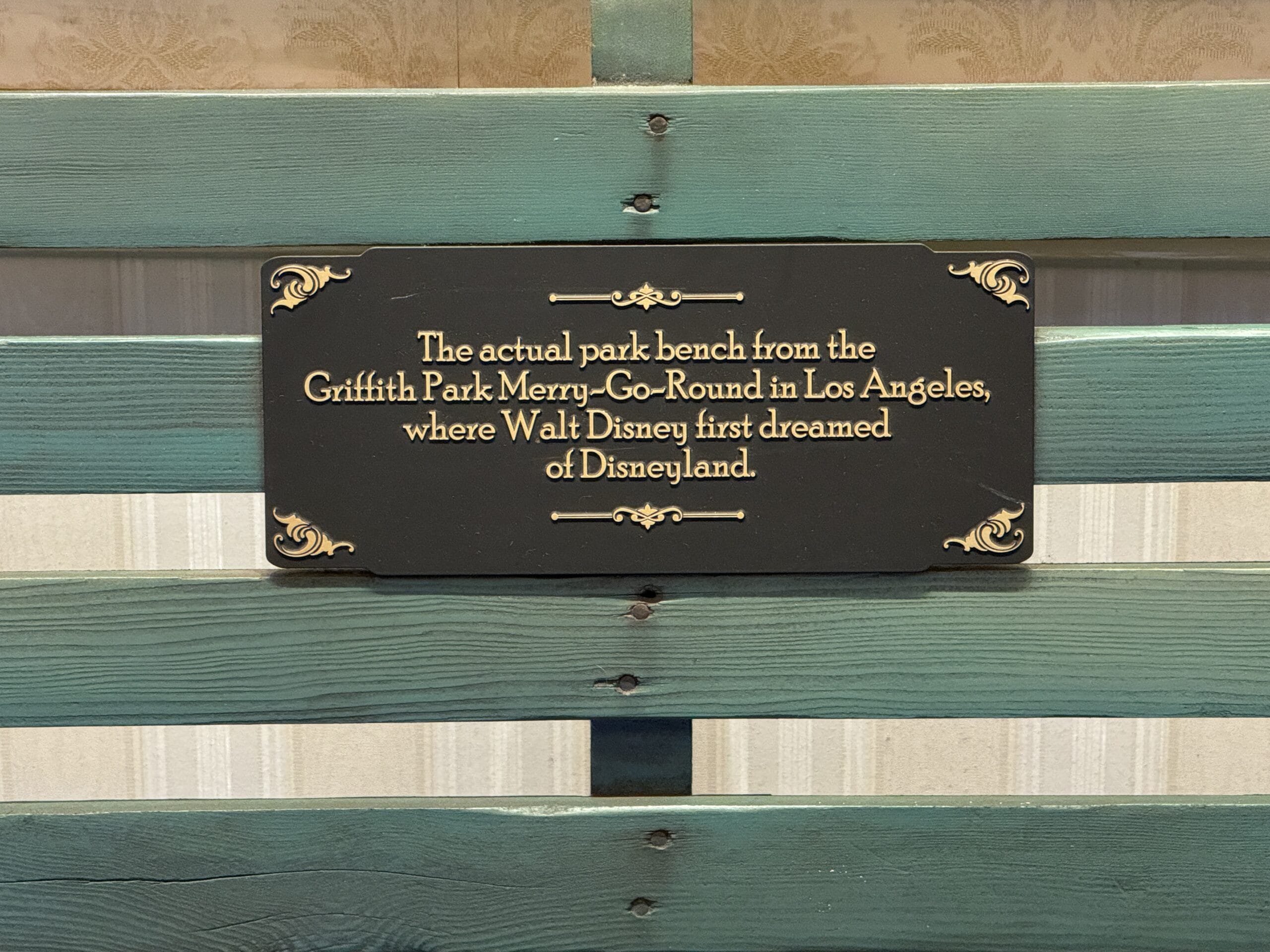 A plaque on a green park bench recalls Griffith Park’s role in inspiring Disneyland history and its timeless magic.