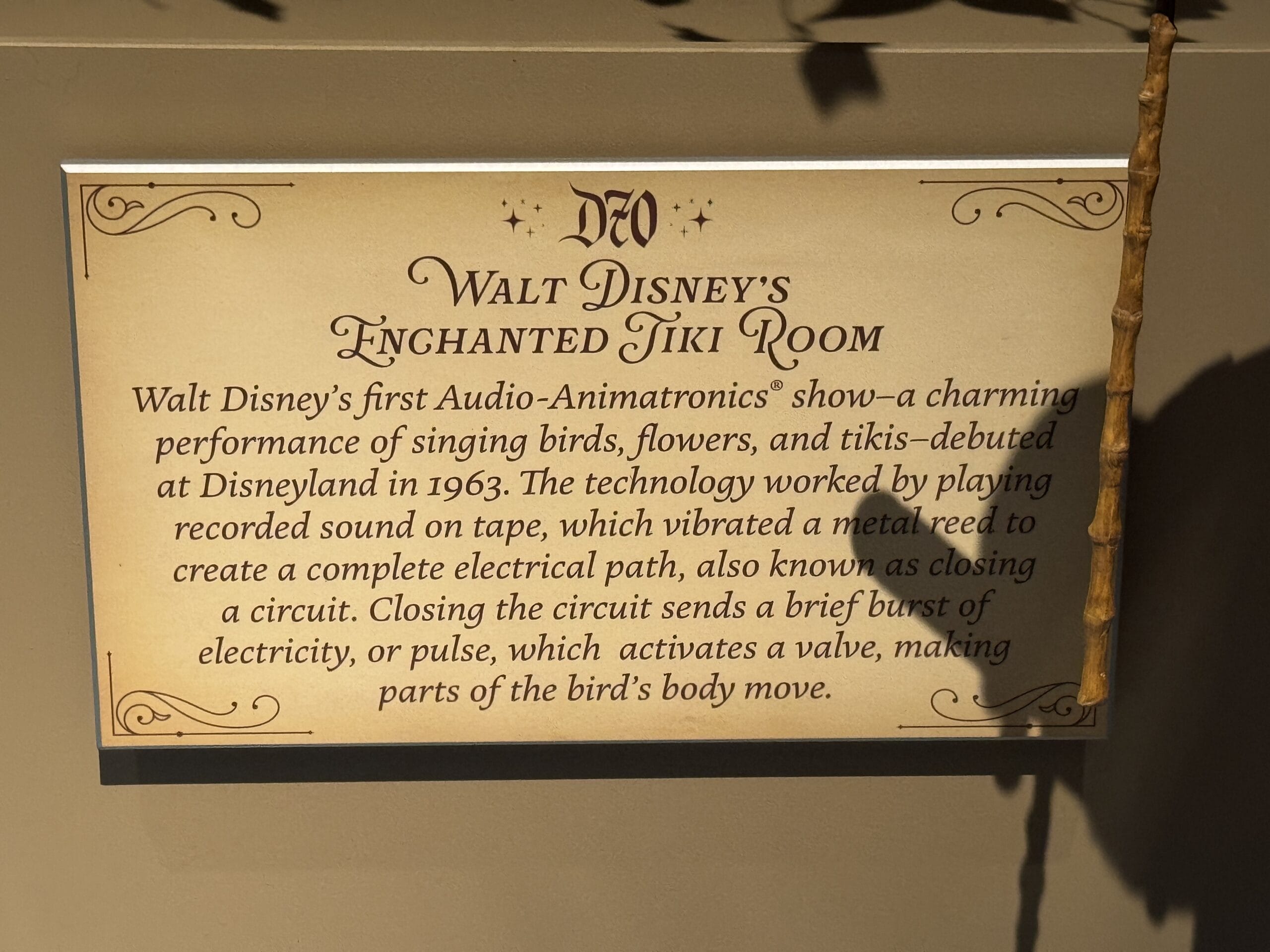 A sign describes Walt Disney's Enchanted Tiki Room, the first Audio-Animatronics show near Main Street Opera House.