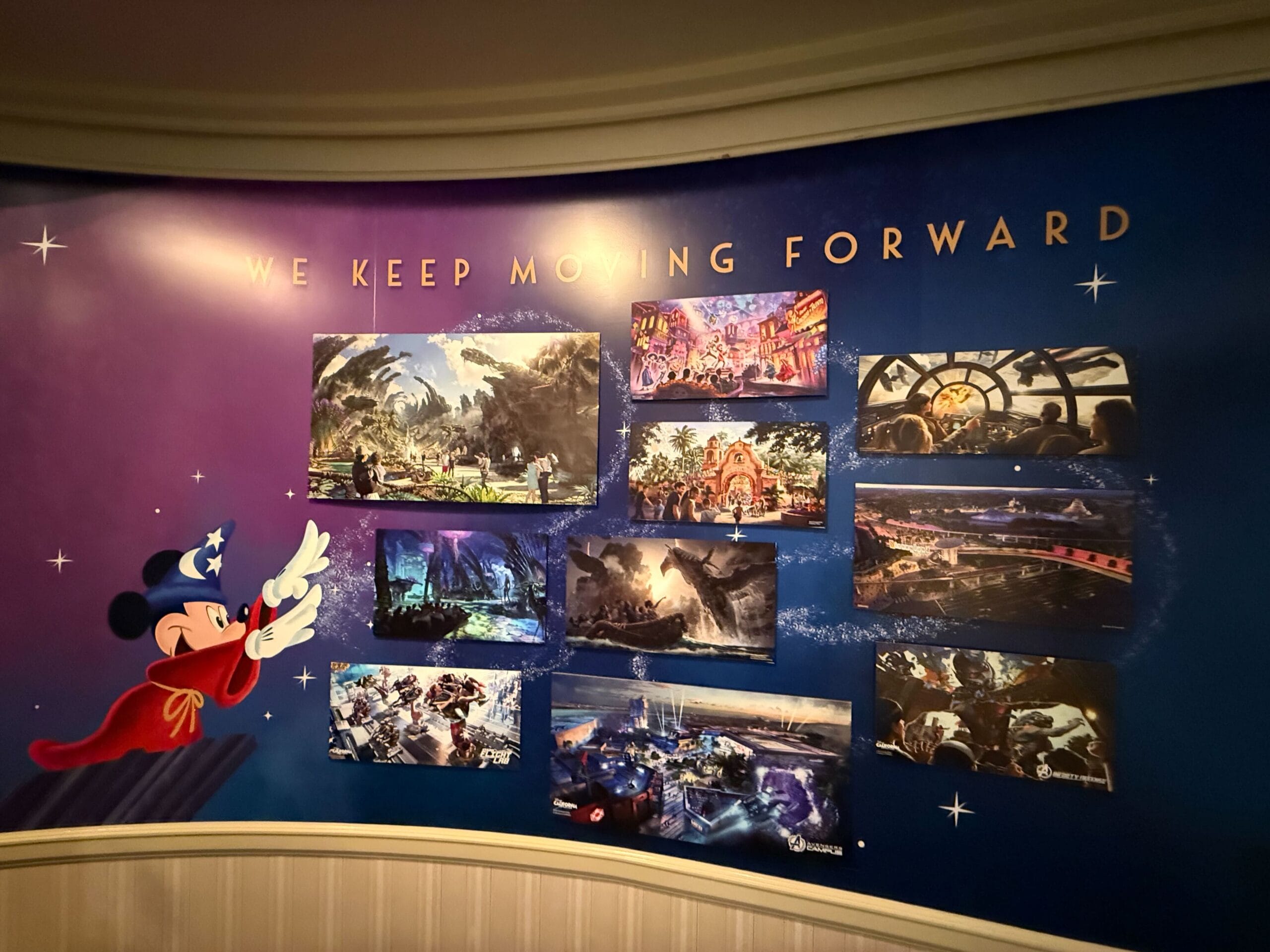 A mural at the Main Street Opera House shows Sorcerer Mickey and "We Keep Moving Forward" above Disney park concept art.