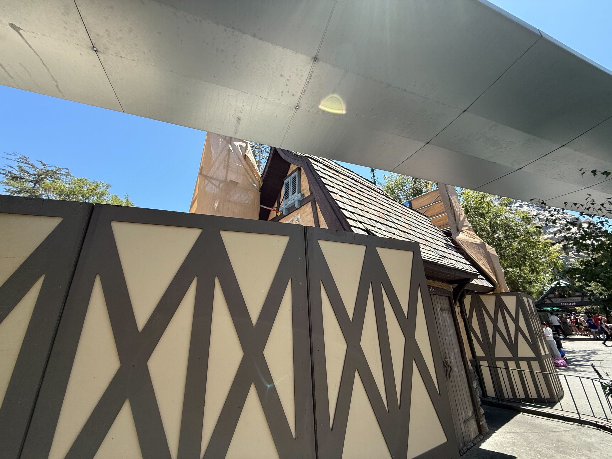 New construction walls with a crisscross pattern block part of a tall, shingled-roof building under renovation.