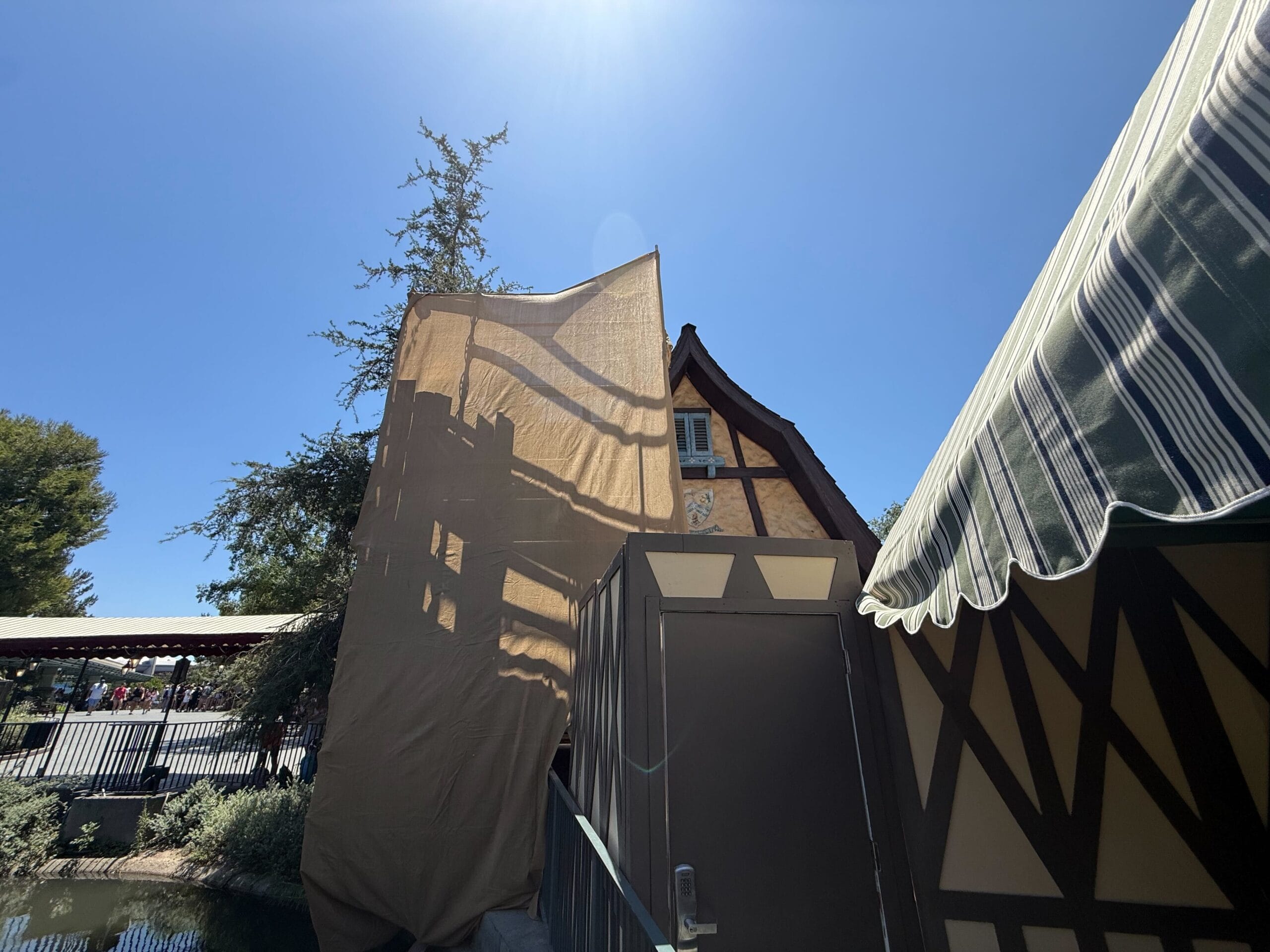 Brown half-timbered building under a clear blue sky, partially covered by tarps during new construction.