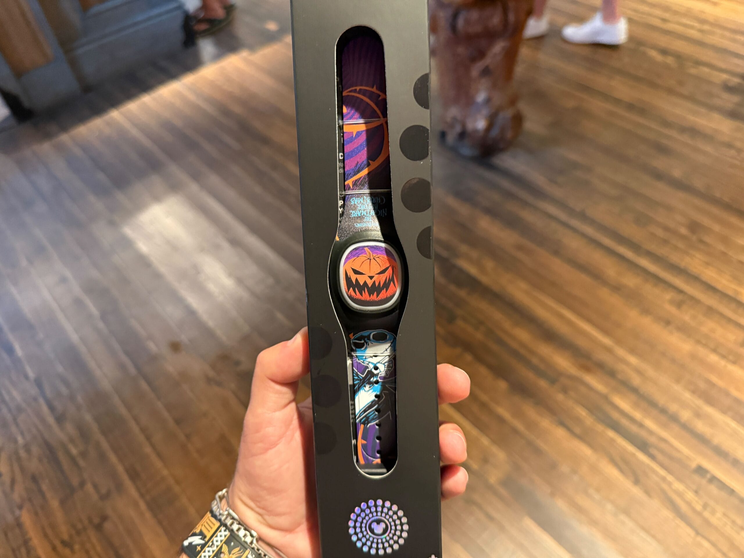 A hand holds a boxed smart wristband featuring a Pumpkin King-style Halloween pumpkin face design.