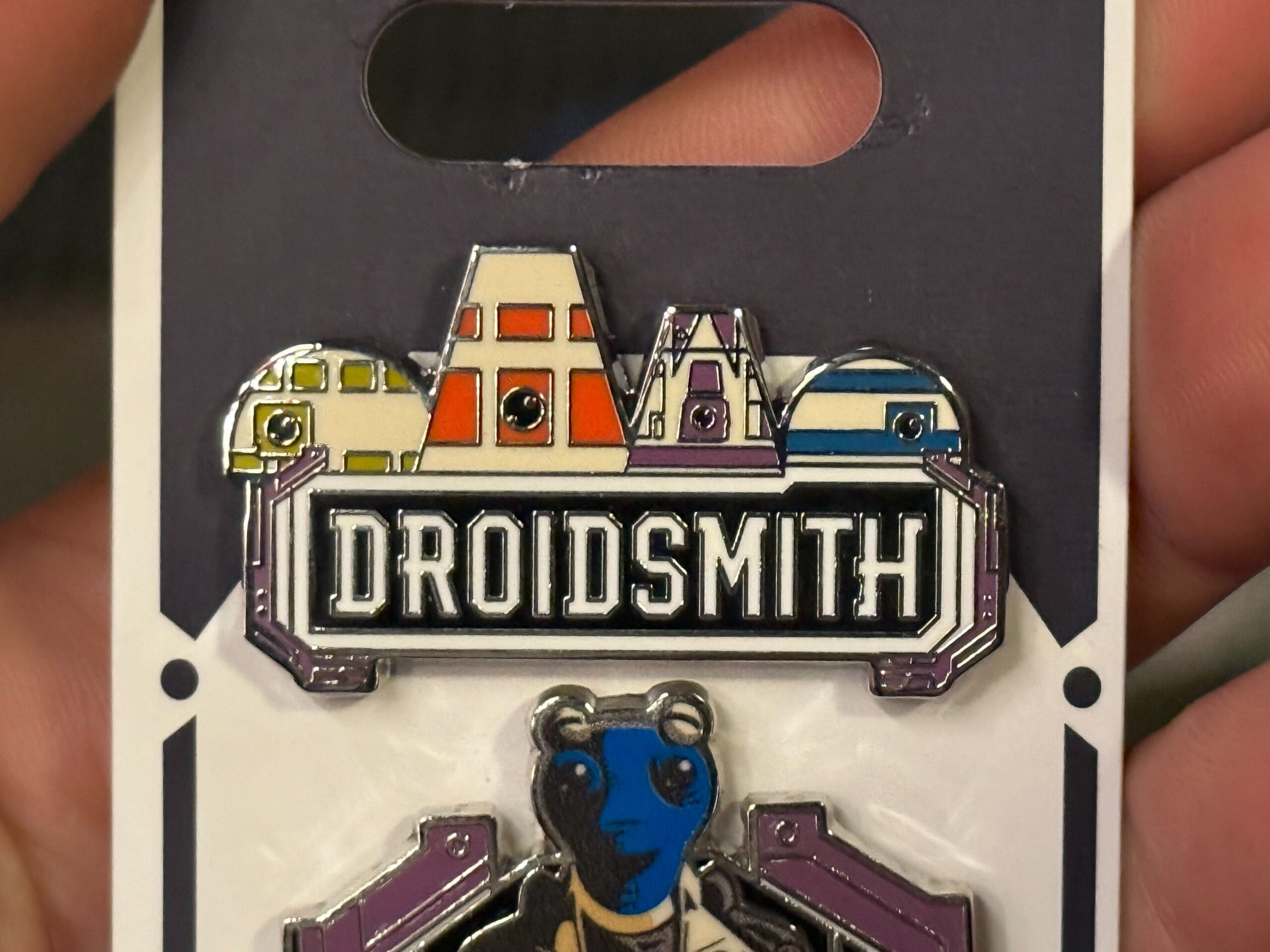 A pin featuring four droid heads and the word "DROIDSMITH" displayed in bold letters on a sign.