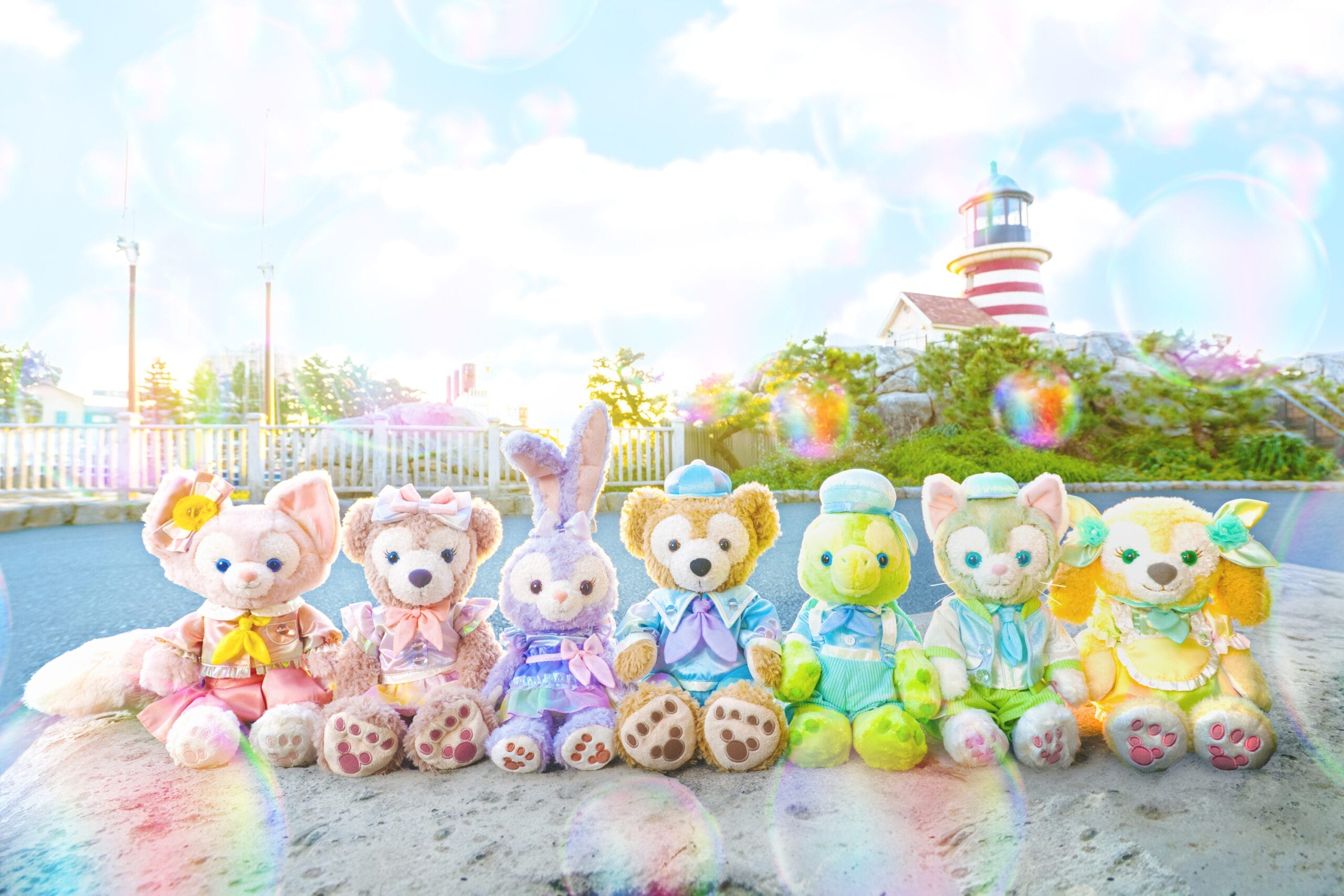 All Seven Duffy and Friends, including Duffy The Disney Bear, sit outdoors with a lighthouse and bubbles in the background.