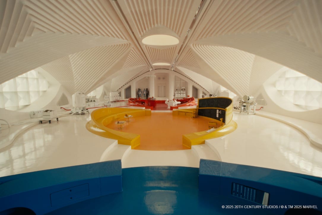 Retro-futuristic white seating area with curved architecture, yellow and orange sections, and other furniture.