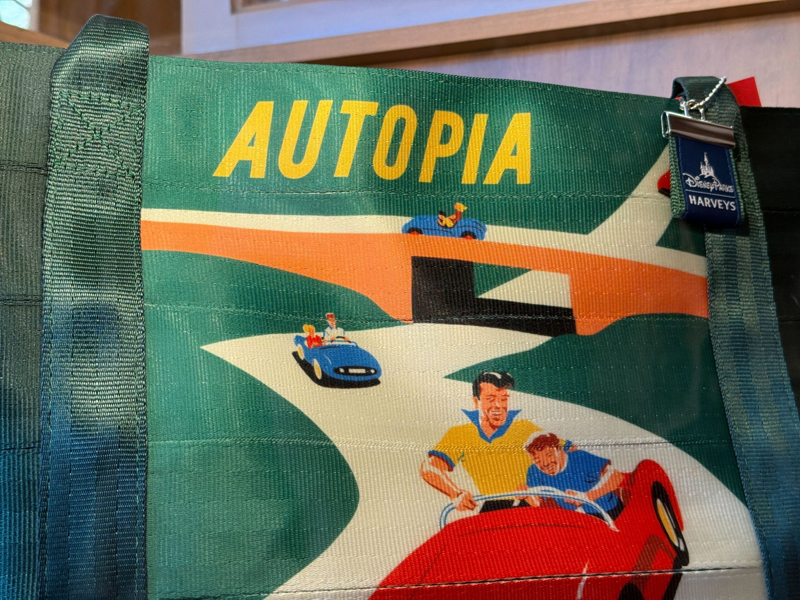A colorful bag with "AUTOPIA" and illustrated people driving race cars on a winding road, with a Disney Parks tag attached.