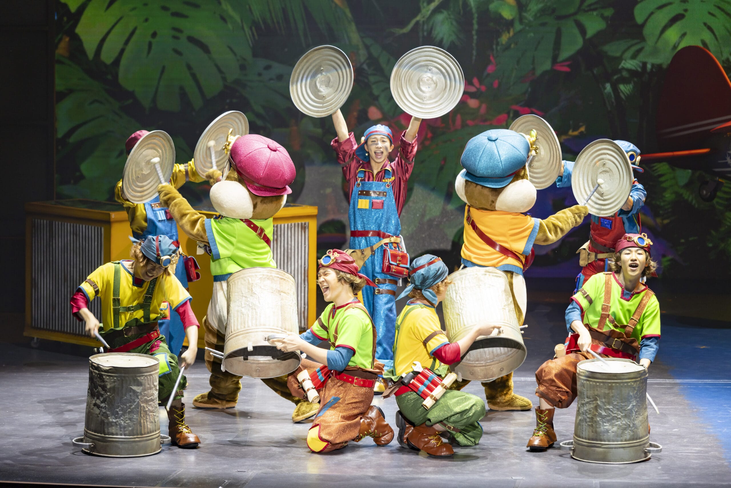 Performers in colorful costumes bang on trash cans at Tokyo DisneySea, where dreams take flight against a jungle backdrop.
