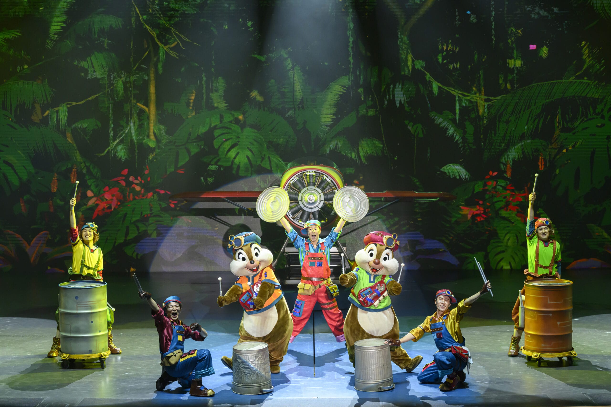 Performers and two chipmunk mascots drum on stage at Tokyo DisneySea, where dreams take flight in a vibrant jungle-themed show.