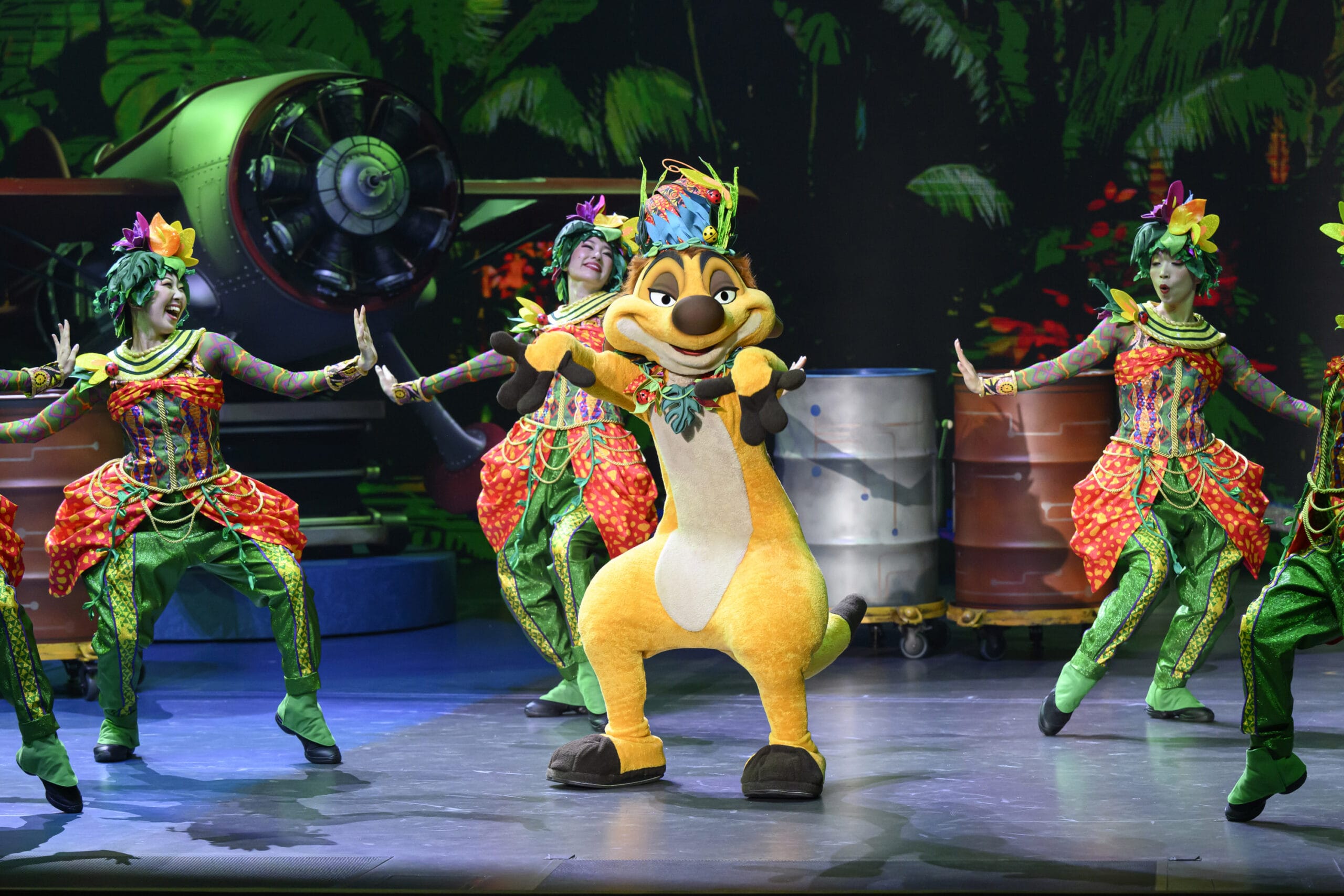 A performer in a Timon costume dances onstage at Tokyo DisneySea as dreams take flight with vibrant jungle-themed dancers.