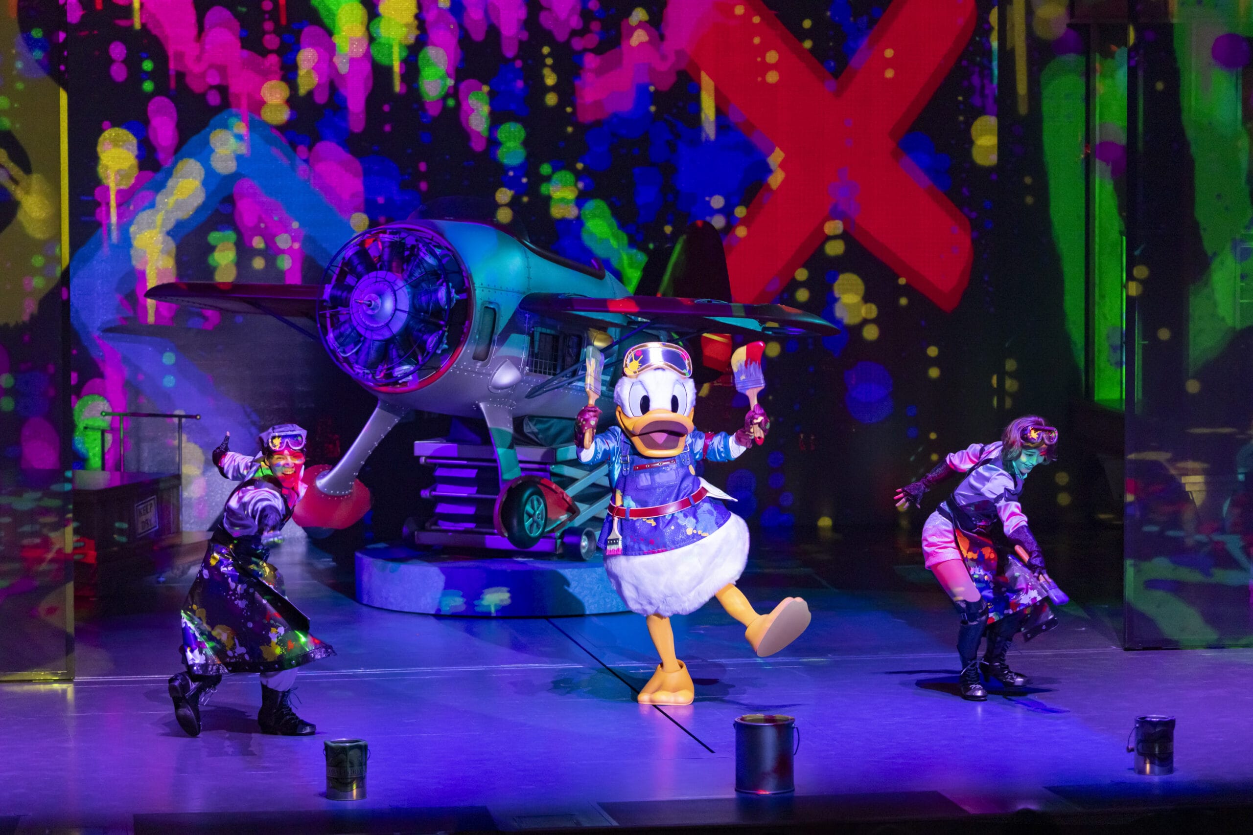 Donald Duck and two dancers perform in vibrant outfits as dreams take flight on a colorful Tokyo DisneySea stage.