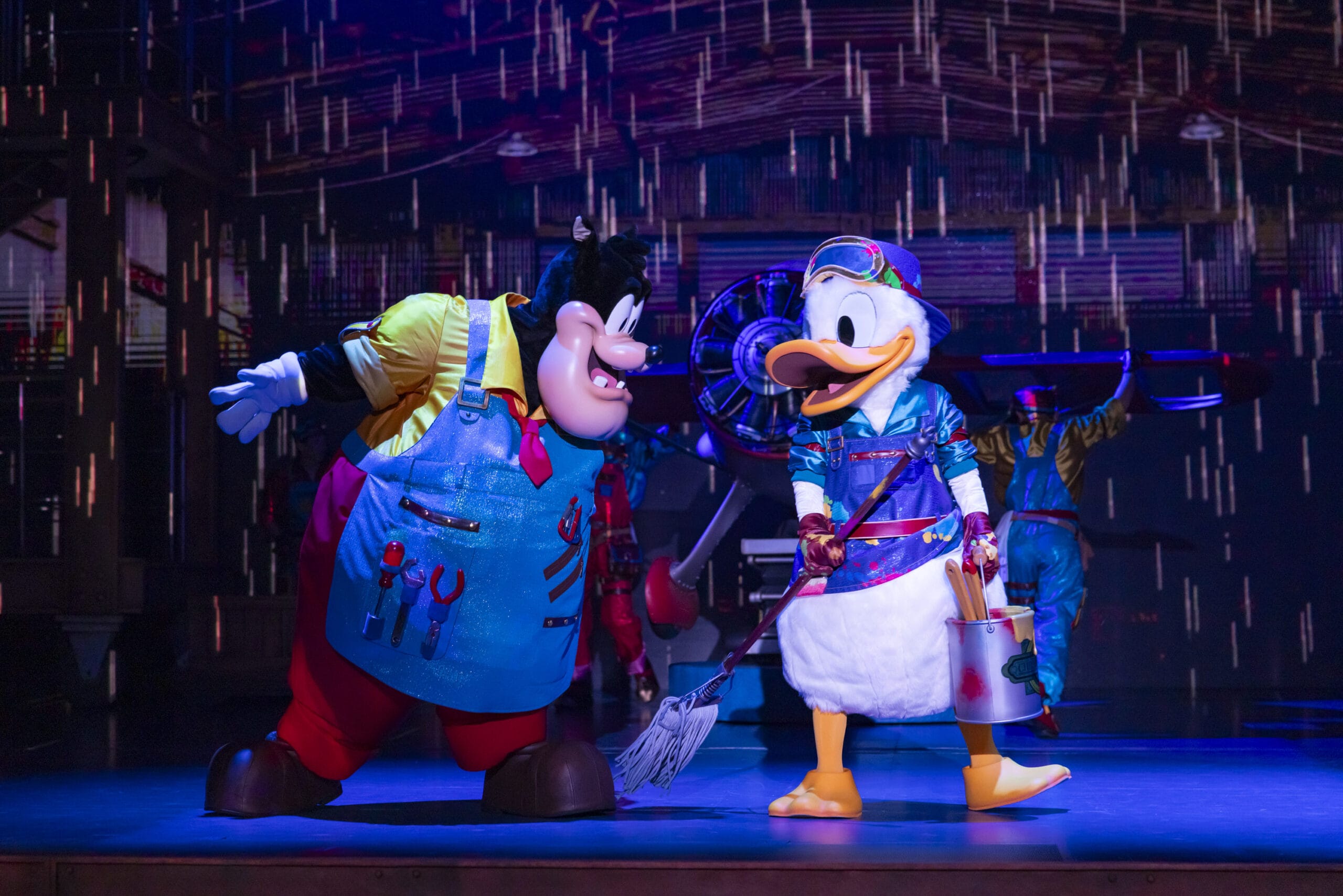 Goofy and Donald Duck, in blue aprons, paint on stage at Tokyo DisneySea where dreams take flight in vibrant color.